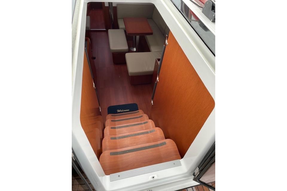 Interior view of 2018 Beneteau Oceanis 45 yacht, featuring wooden stairs and cozy seating area.