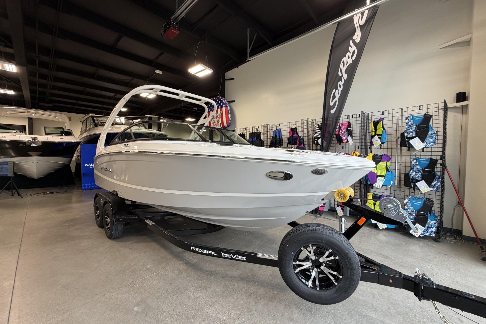 2027 Regal LS2 boat on trailer in showroom, surrounded by colorful life jackets.