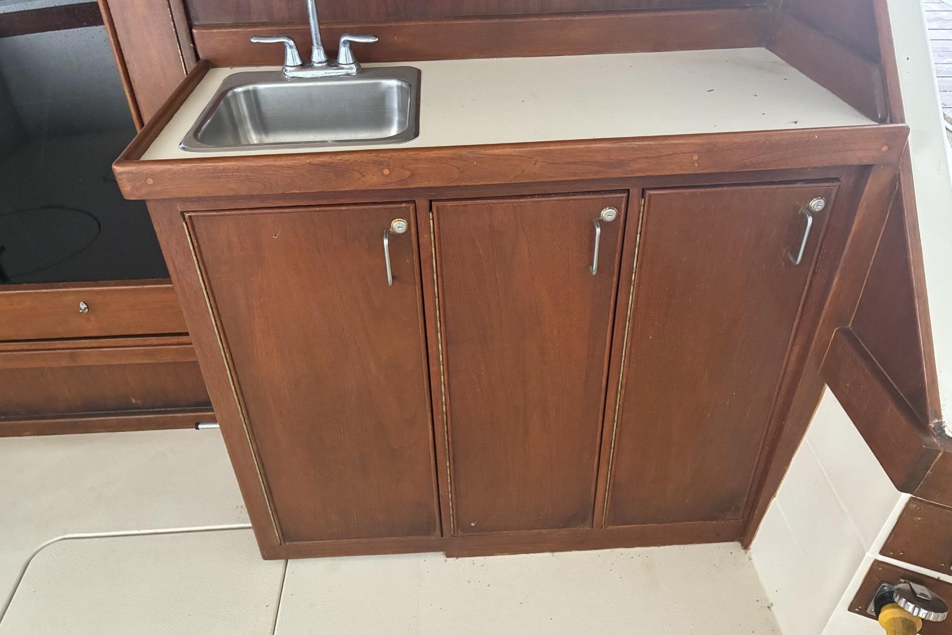 1980 Chris-Craft 360 Commander interior with wooden cabinetry and stainless steel sink.