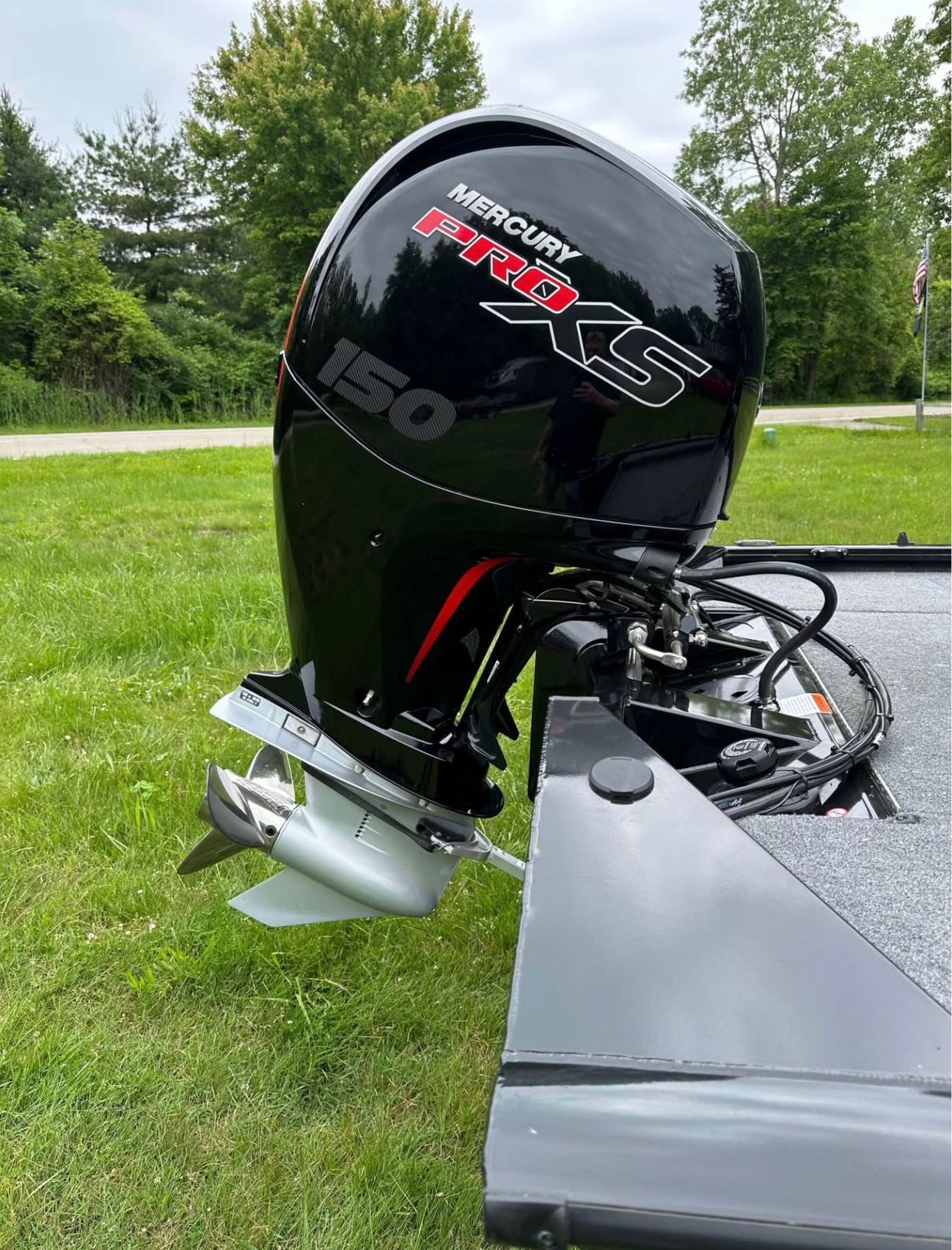 A Mercury Pro XS 150 outboard motor is mounted on a Bass Tracker 195TXW boat. The boat is on a grassy area.