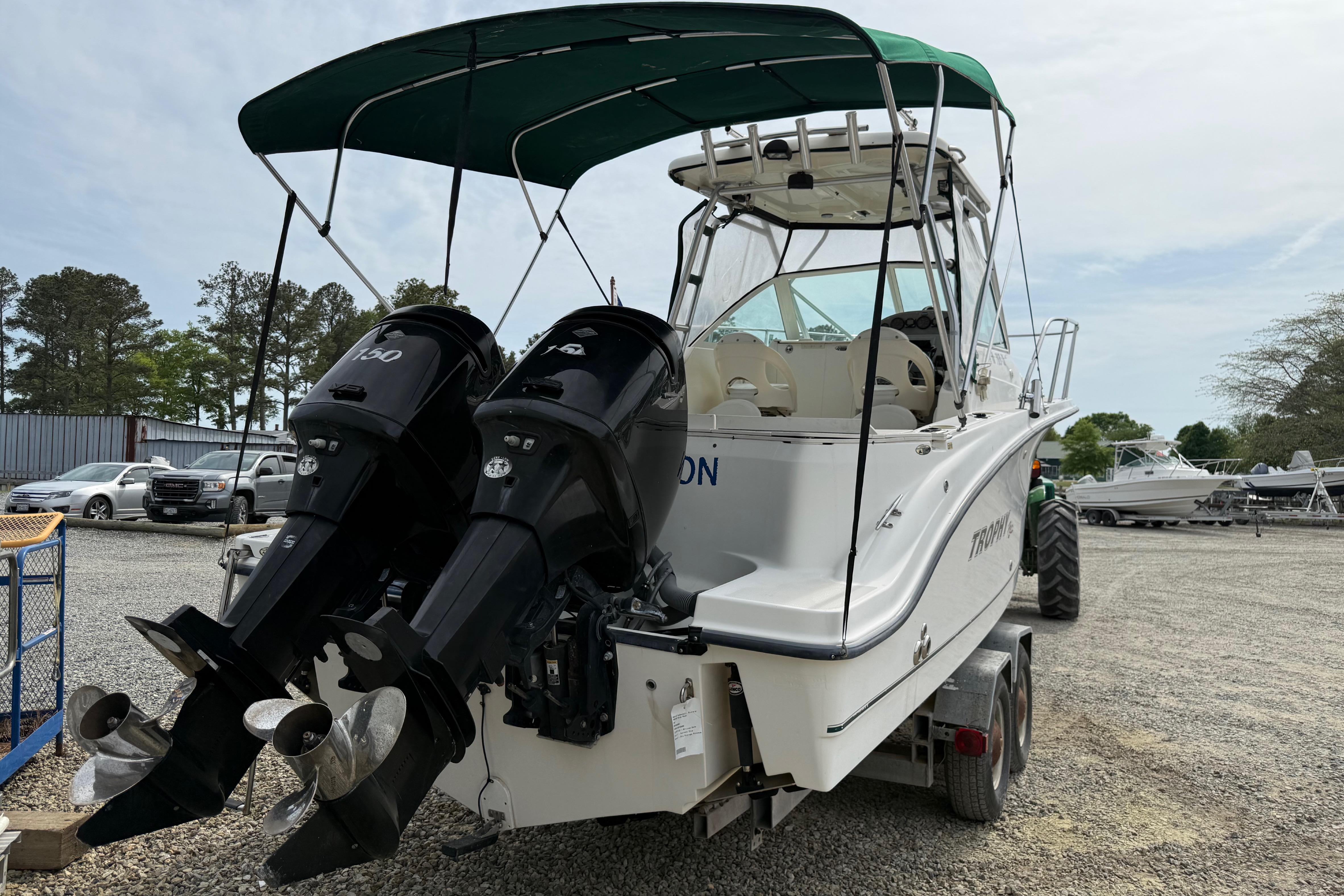 2006 Trophy 2502 Walkaround boat with dual outboard motors and canopy, parked on a trailer.