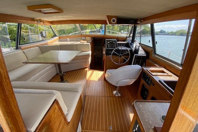 1985 Bayliner 3870 Motoryacht interior with helm, seating, and dining area, overlooking water.
