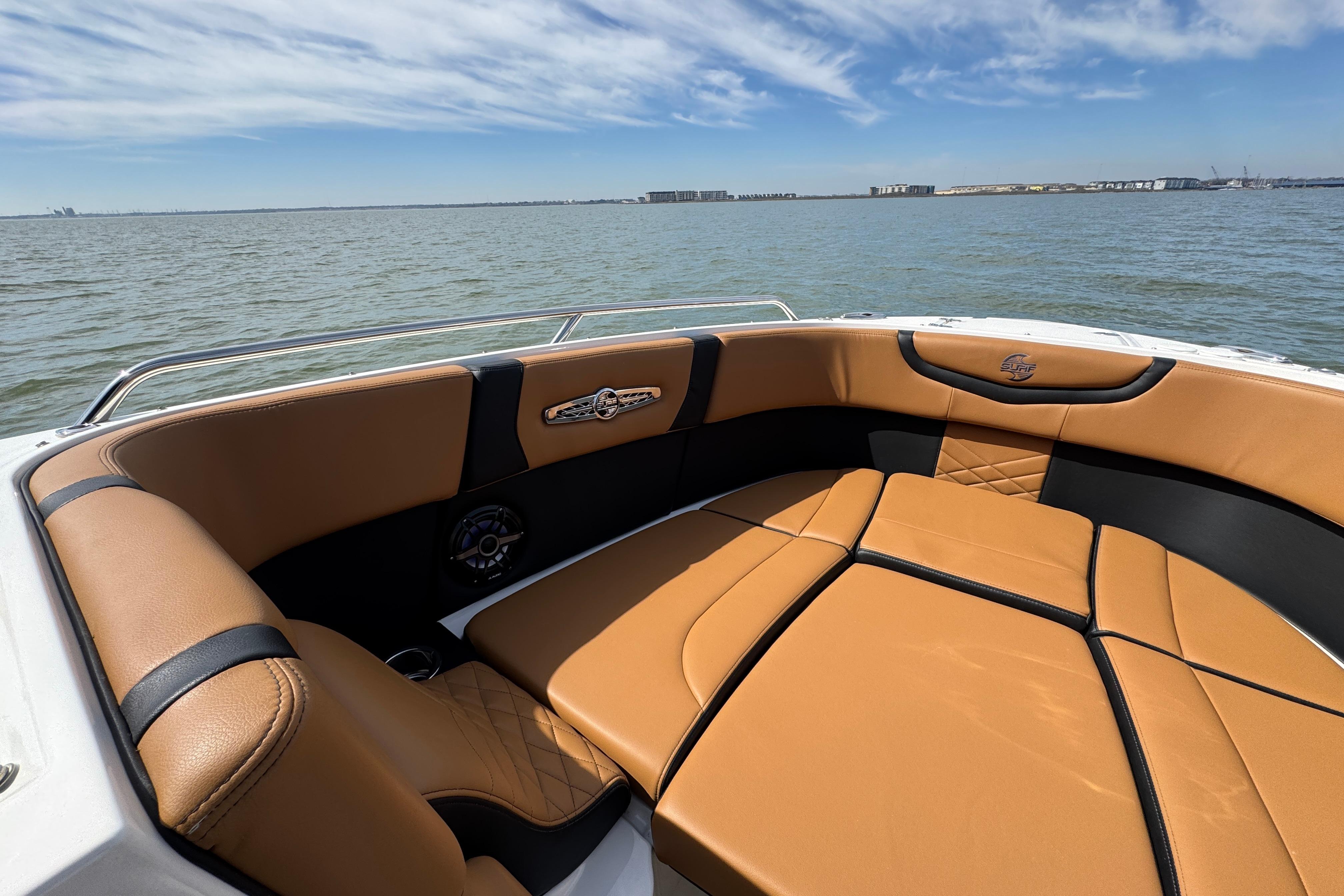 2023 Chaparral 26 Surf boat interior with tan leather seating on a sunny day.