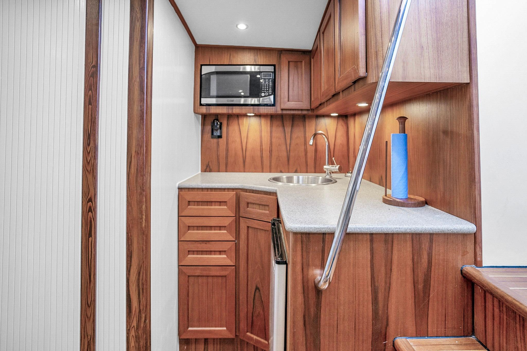 Compact wooden kitchen interior on a 1994 Daytona Express boat, featuring a microwave and sink.