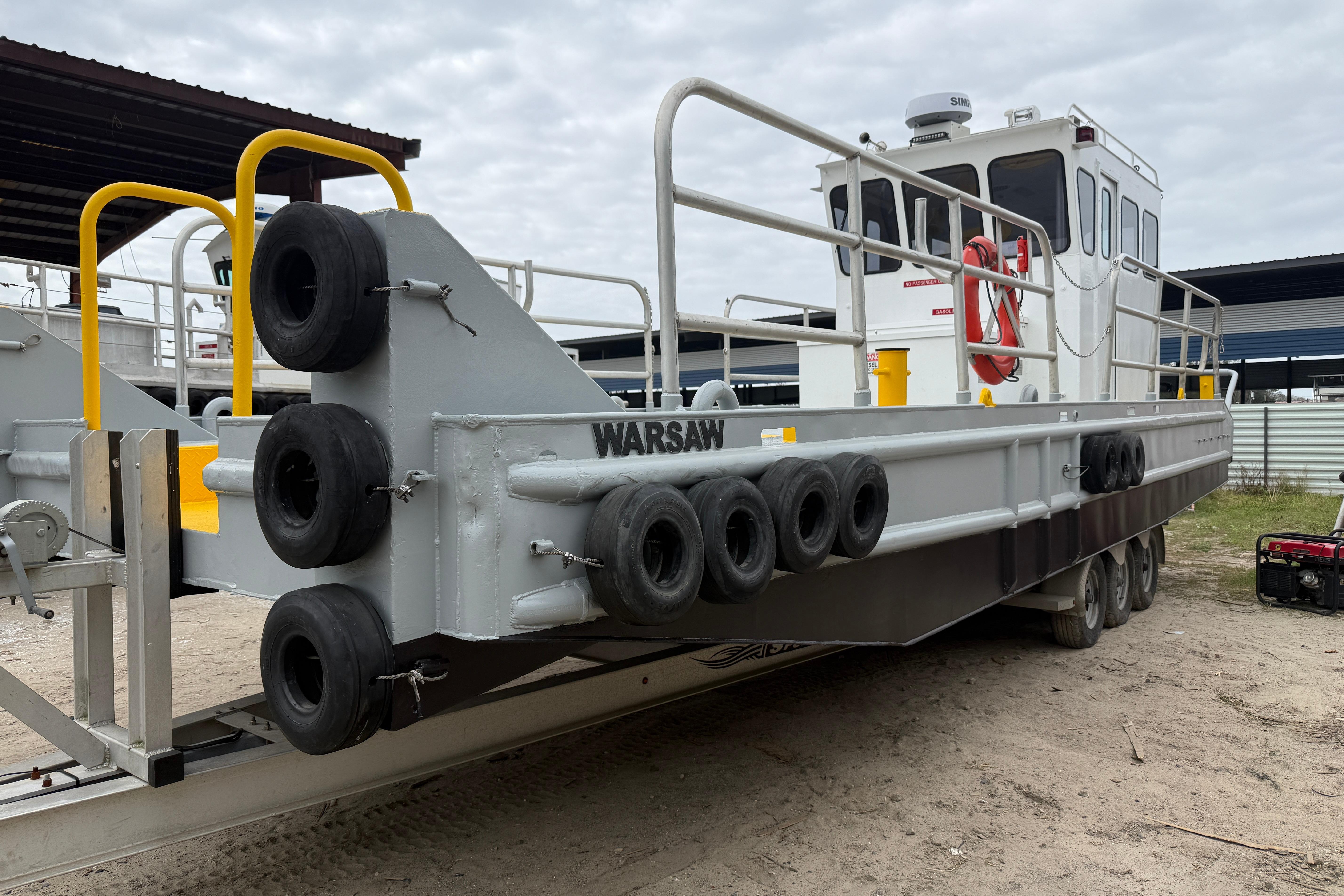 Custom Aluminum Work Boat 34x10, 2010 model, docked with safety railings and tires.