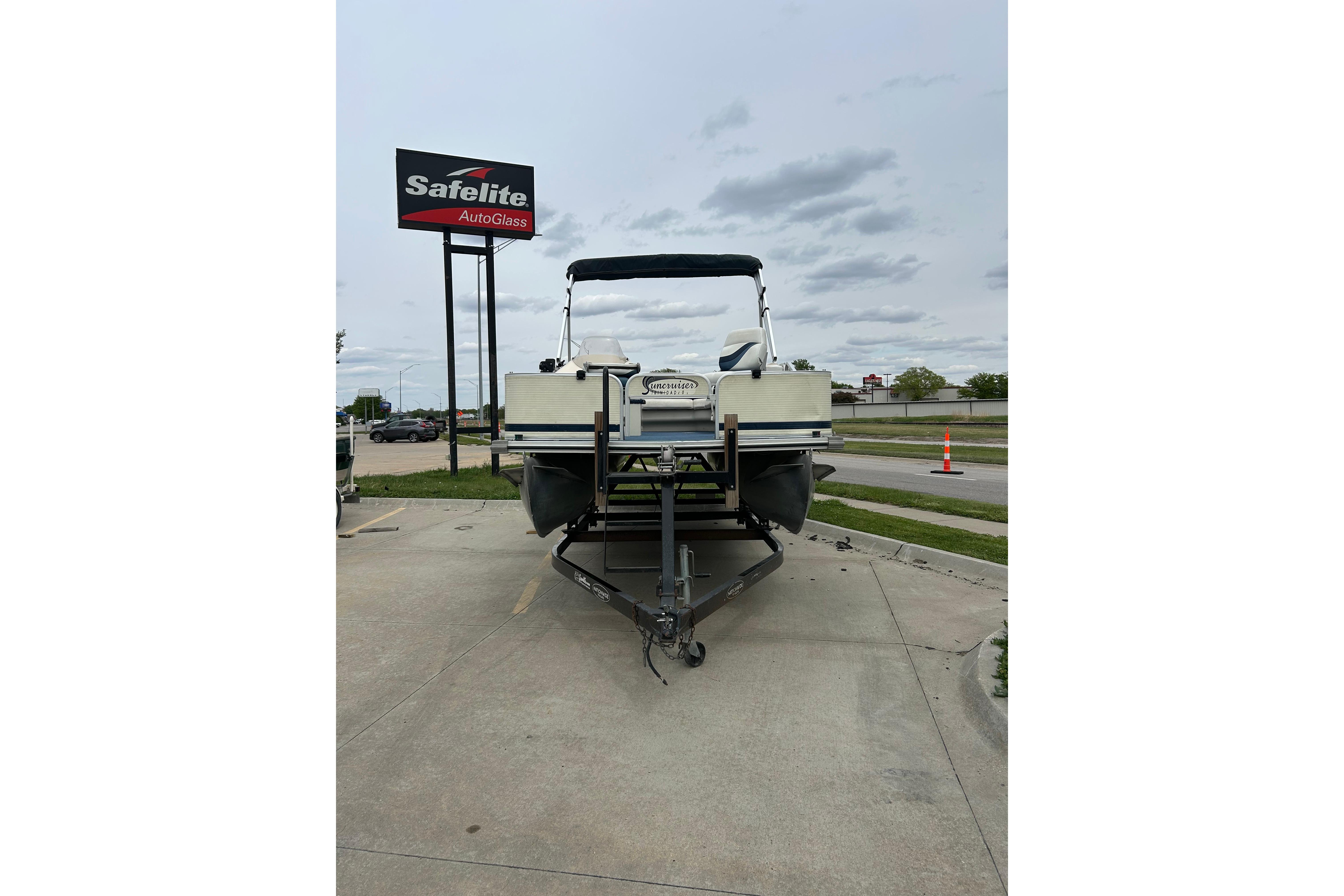 2002 Lowe Trinidad 200 pontoon boat on trailer near Safelite AutoGlass sign.