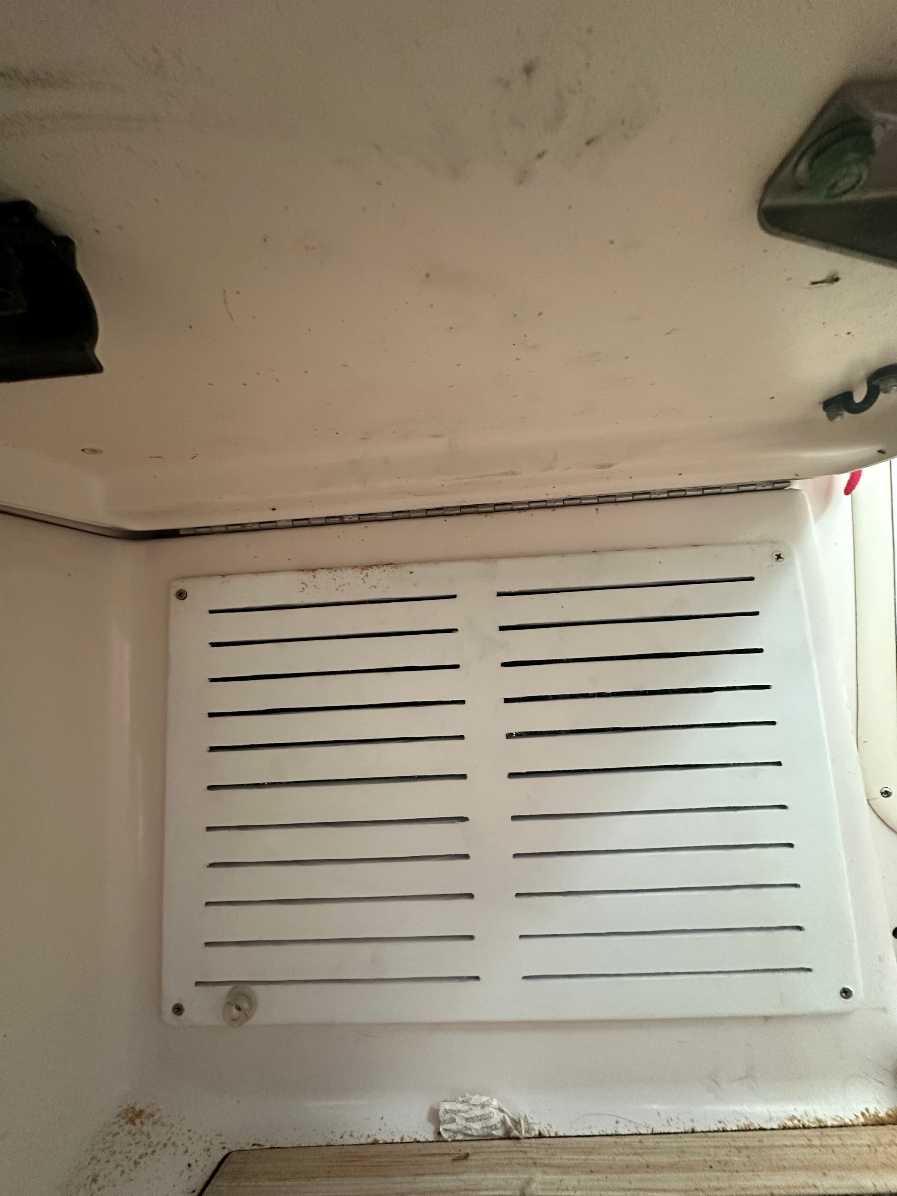Ventilation grille in a boat, surrounded by white surfaces.