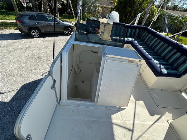 2020 Beachcat 20 boat with open storage compartment and striped seating, parked near a car.