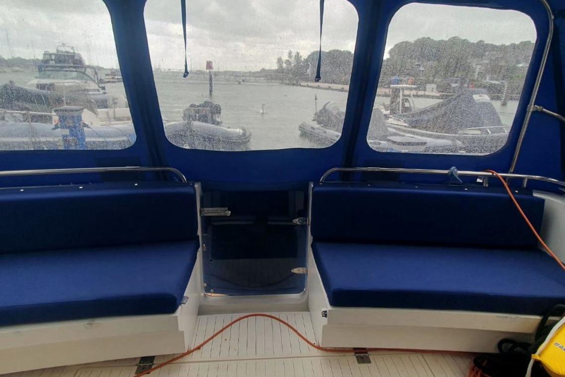 Interior of a 1989 Princess 35 boat with blue seating and marina view.