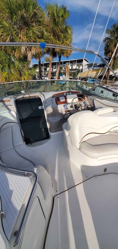 The image shows the cockpit of a 2002 Wellcraft 3300 Martinique with white seating and palm trees in the background.