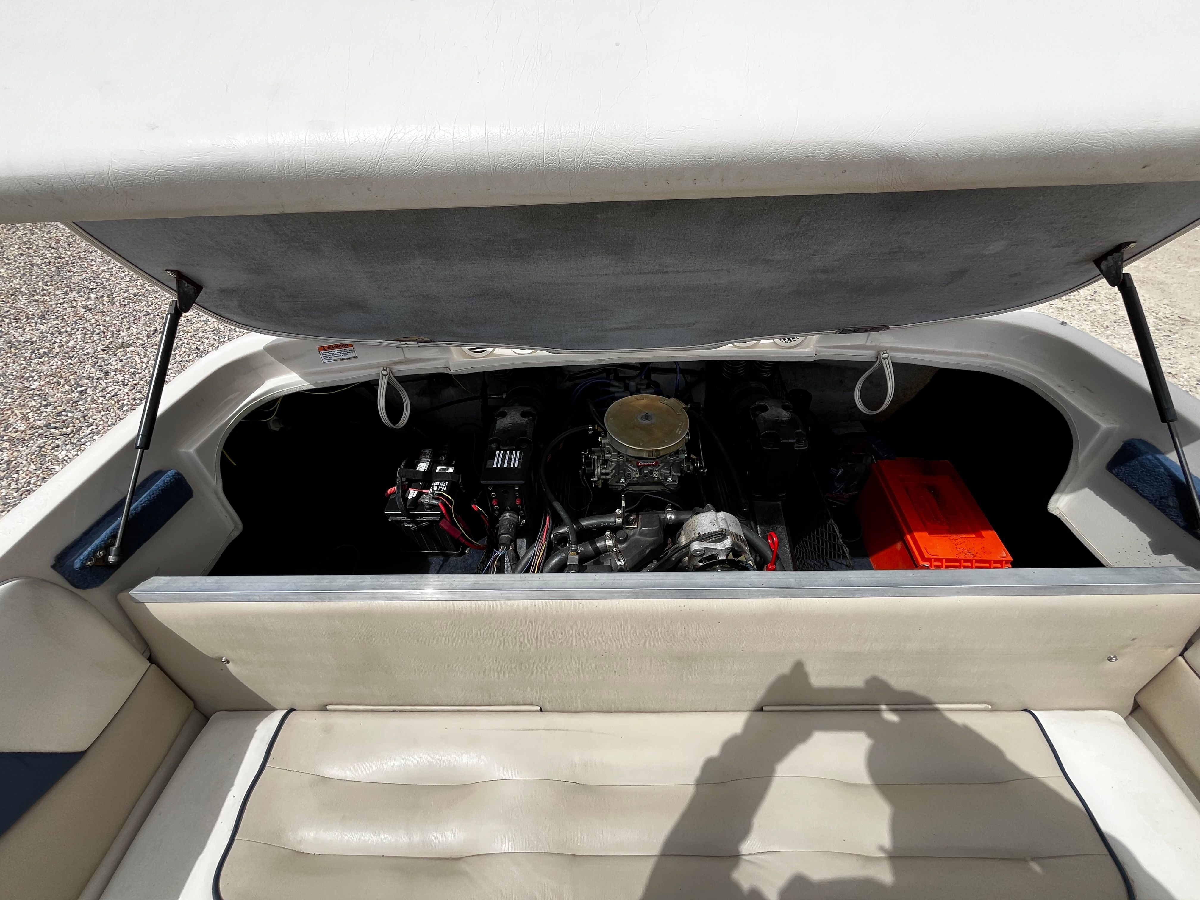 The engine compartment of a 1998 Glastron SE199 is open, revealing the engine and a battery.