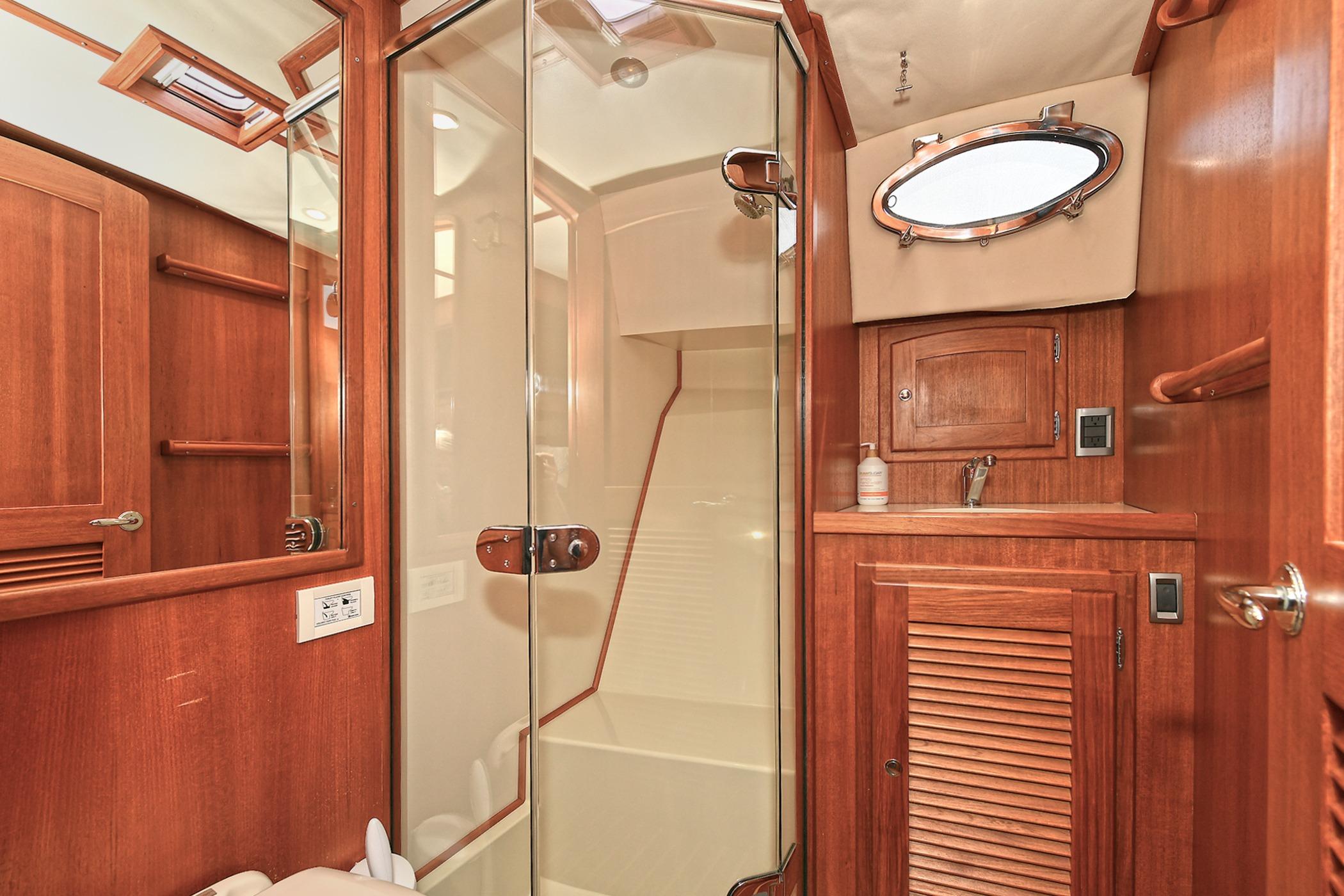 Luxurious 2005 San Juan Downeast Express yacht bathroom with wood accents and glass shower.