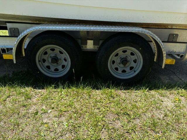 A boat trailer with two wheels is parked on grass.