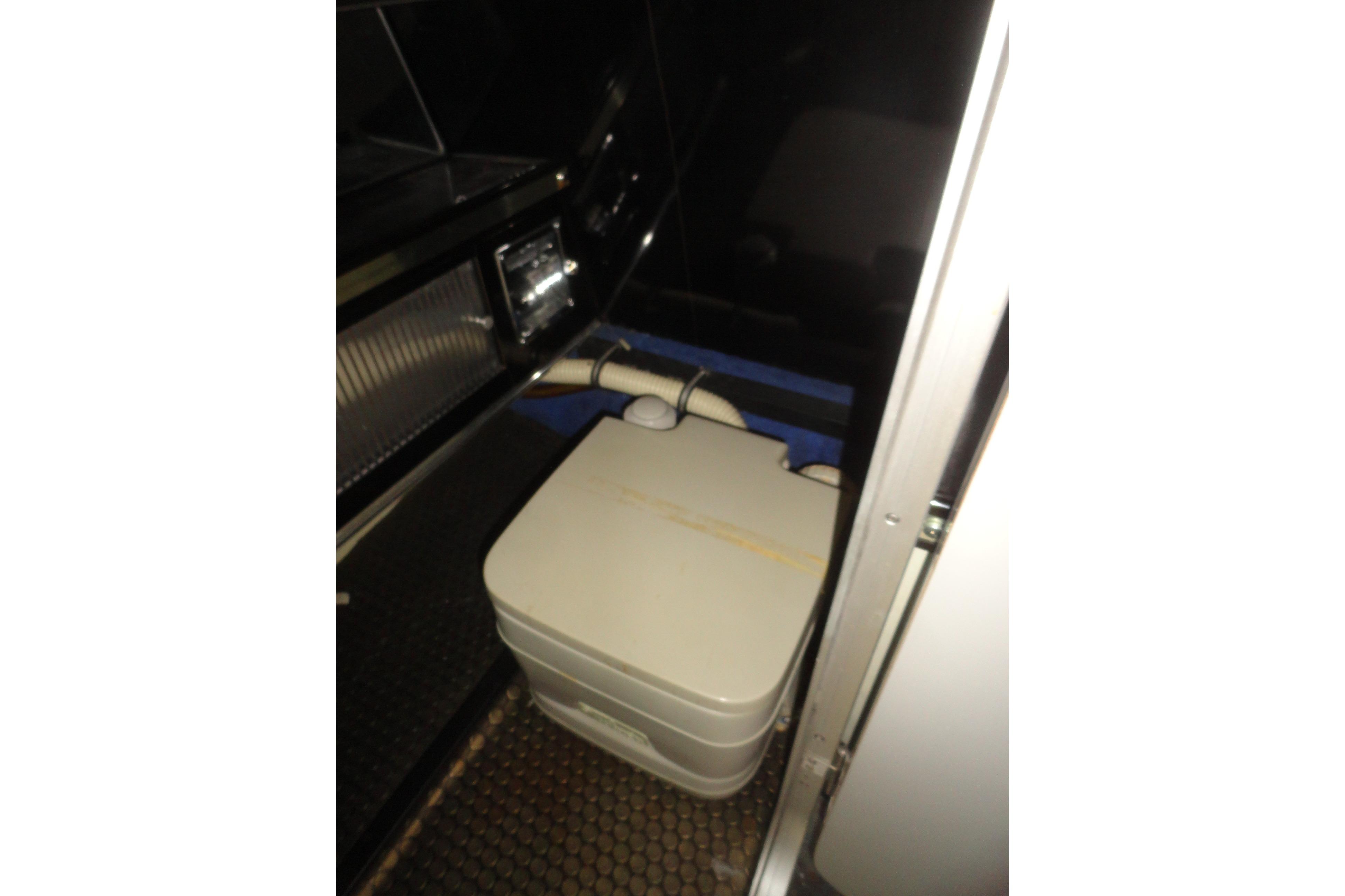 Interior of 1988 Wellcraft 34 Scarab boat featuring compact portable toilet.