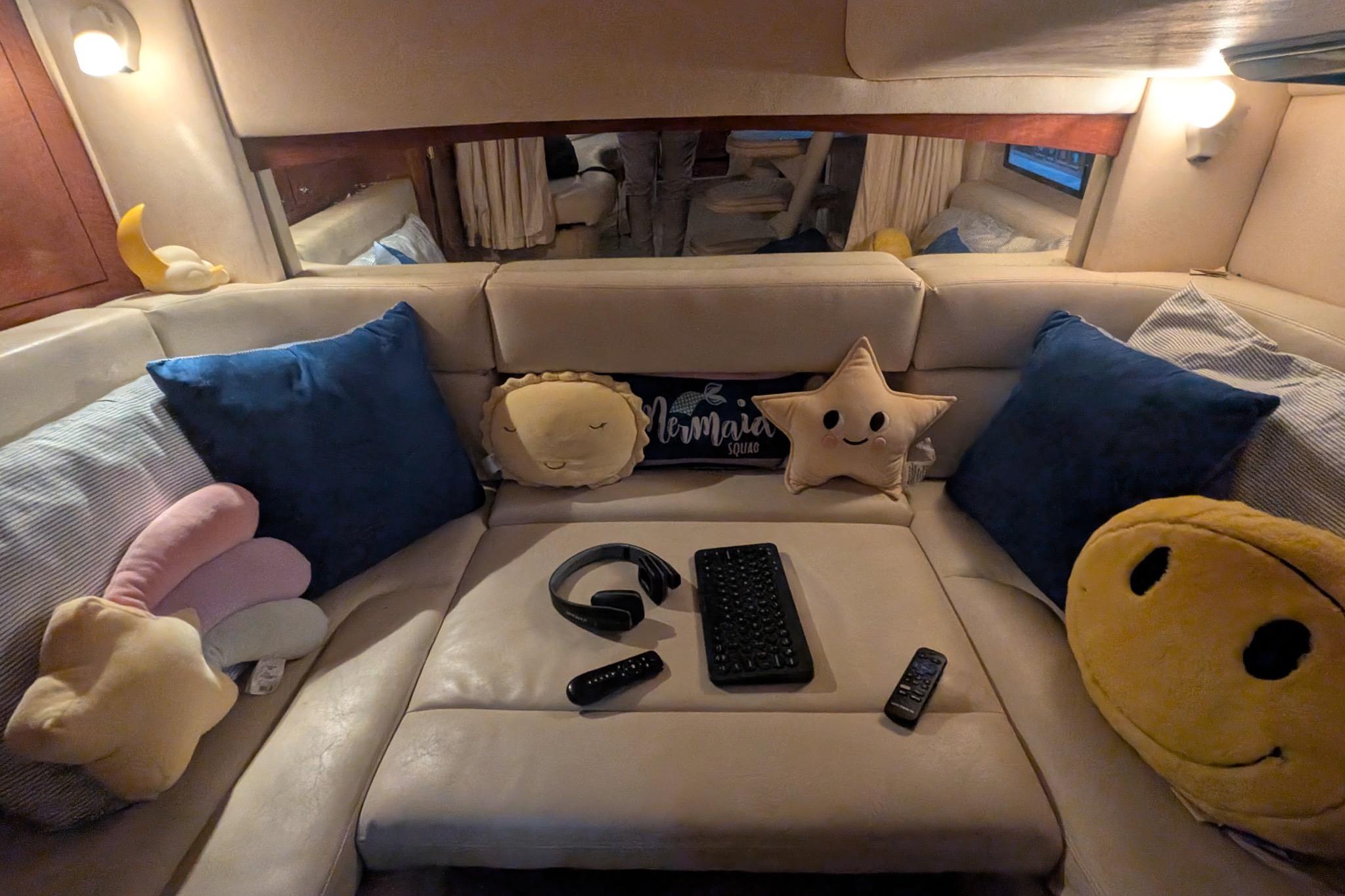 Cozy interior of 2002 Sea Ray Sundancer 320 with plush pillows and electronic gadgets.
