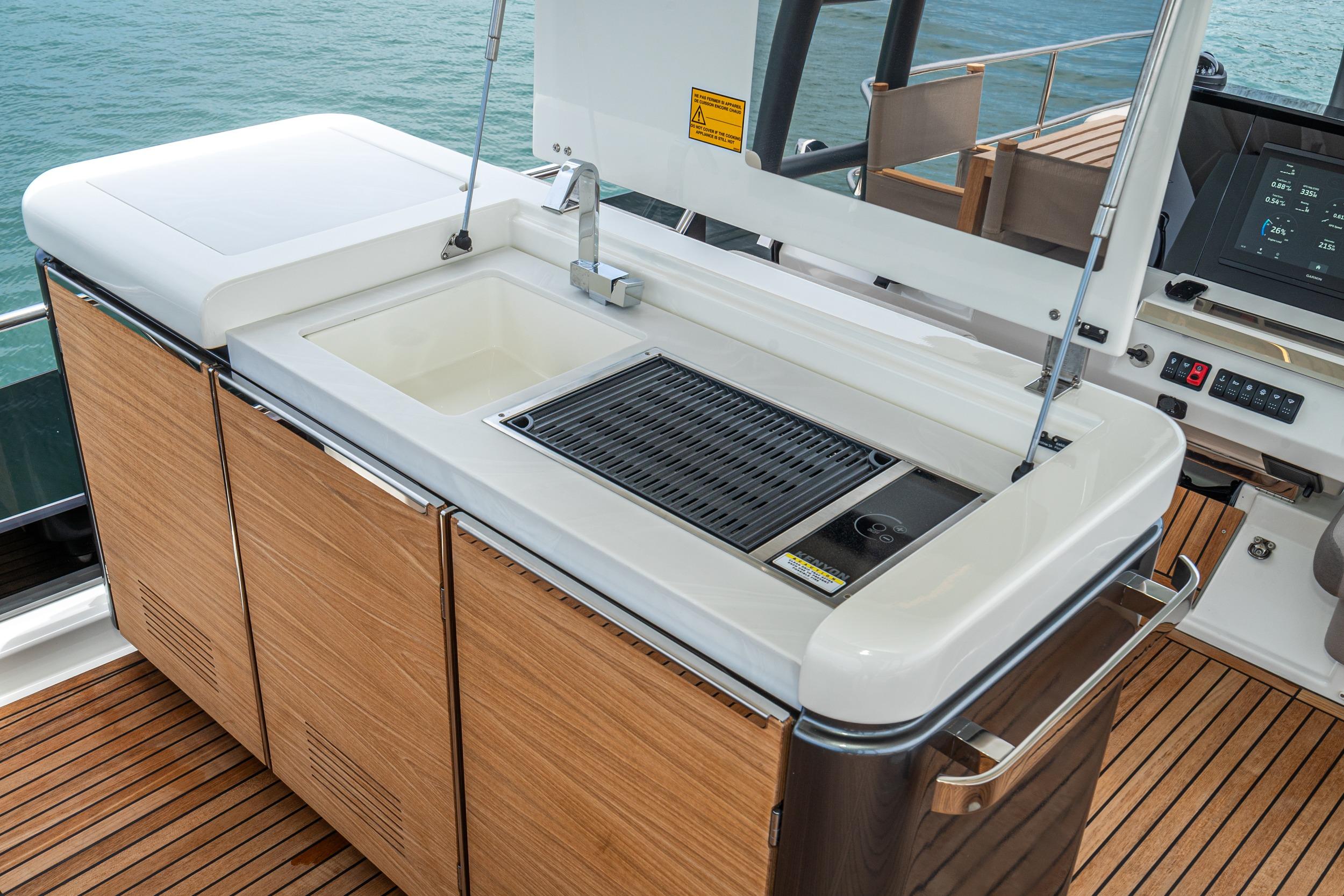 Outdoor kitchen on 2024 Prestige X60 yacht with sink and grill, overlooking the ocean.