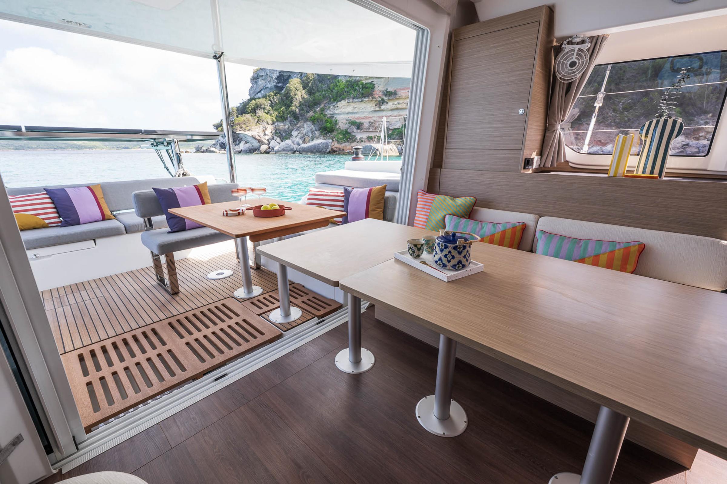Luxurious interior of 2025 Lagoon 38 catamaran with colorful cushions and scenic ocean view.