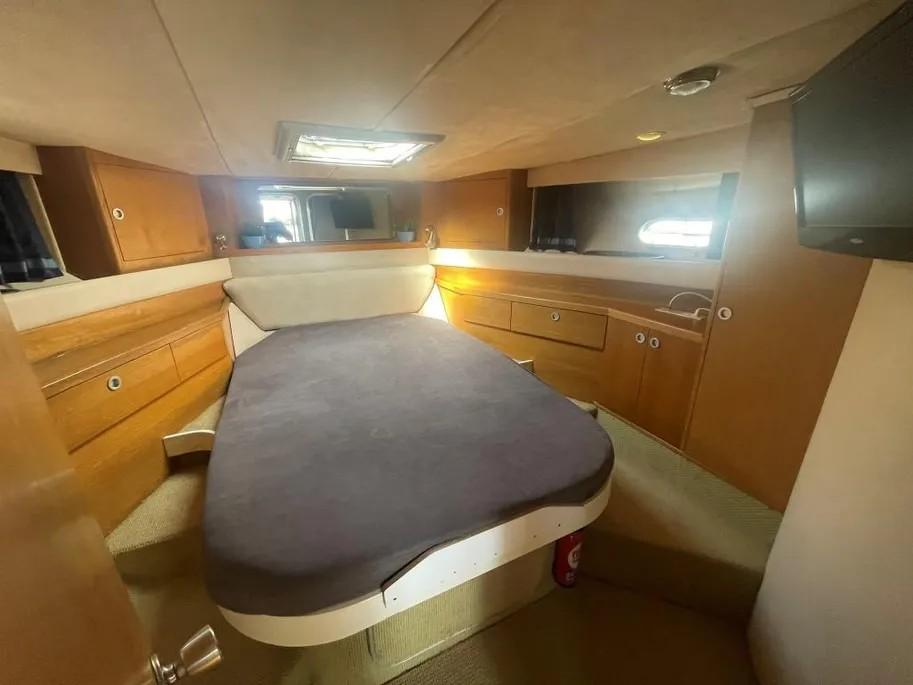 1985 Princess Sedan Flybridge cabin with bed, wooden cabinets, and small windows.