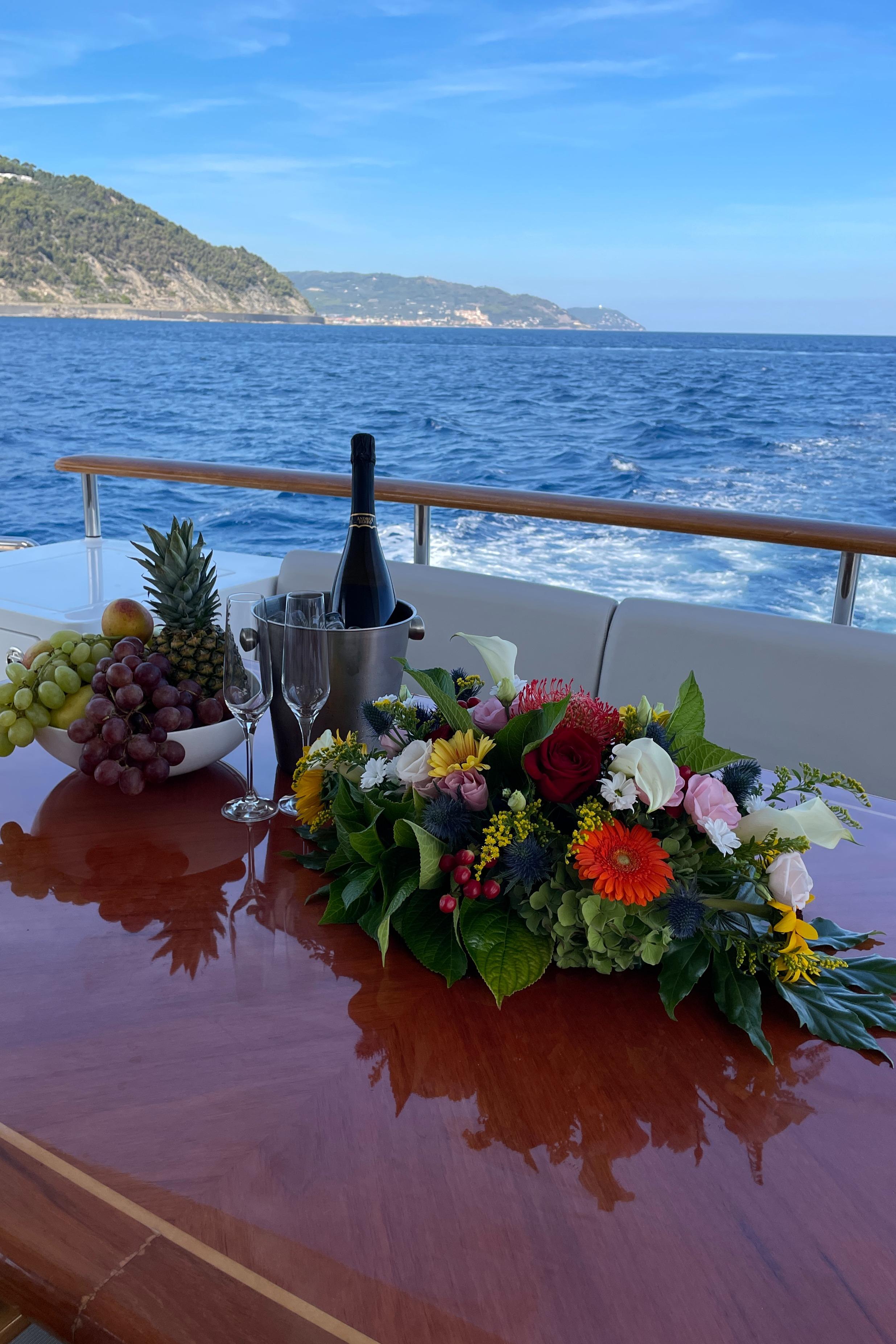 Luxurious Heesen Versilcraft yacht deck with flowers, wine, and ocean view, 2000 model.