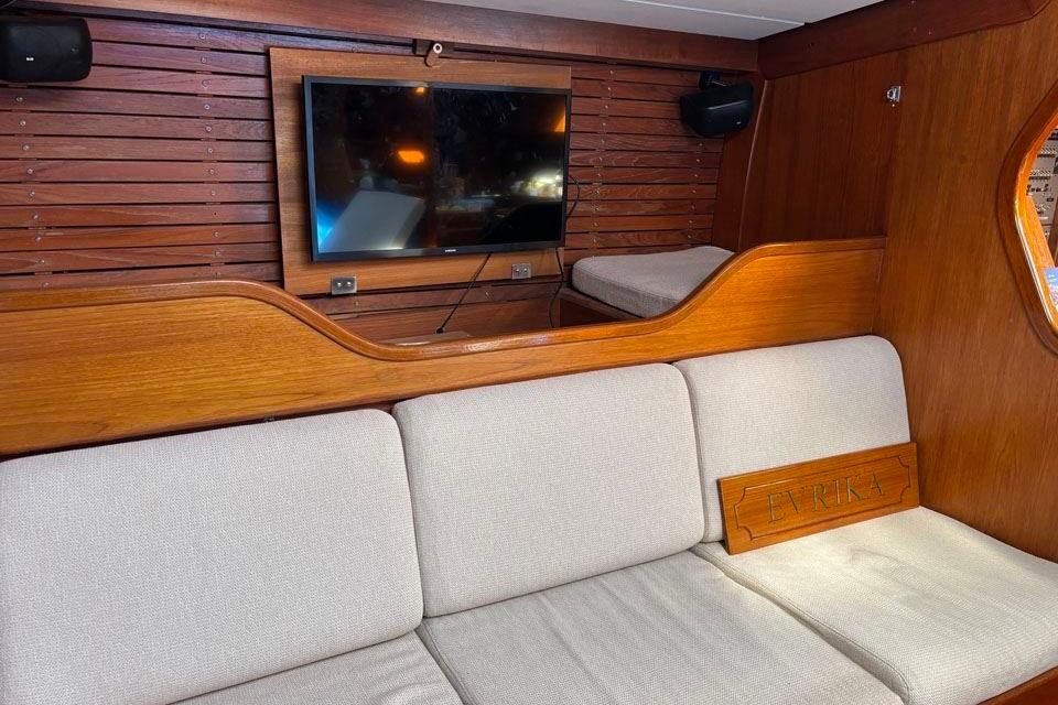 Interior of 1982 Nautor Swan 65 yacht with wooden paneling and cozy seating area.