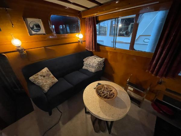 1951 Chris-Craft Catalina interior with cozy seating, round table, and nautical decor.
