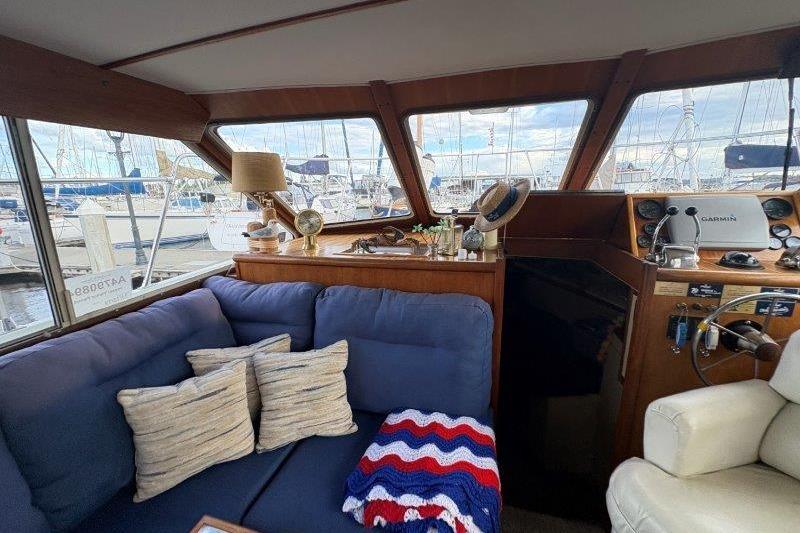 1987 Tollycraft 34 Sundeck Motor Yacht interior with blue sofa, nautical decor, and marina view.