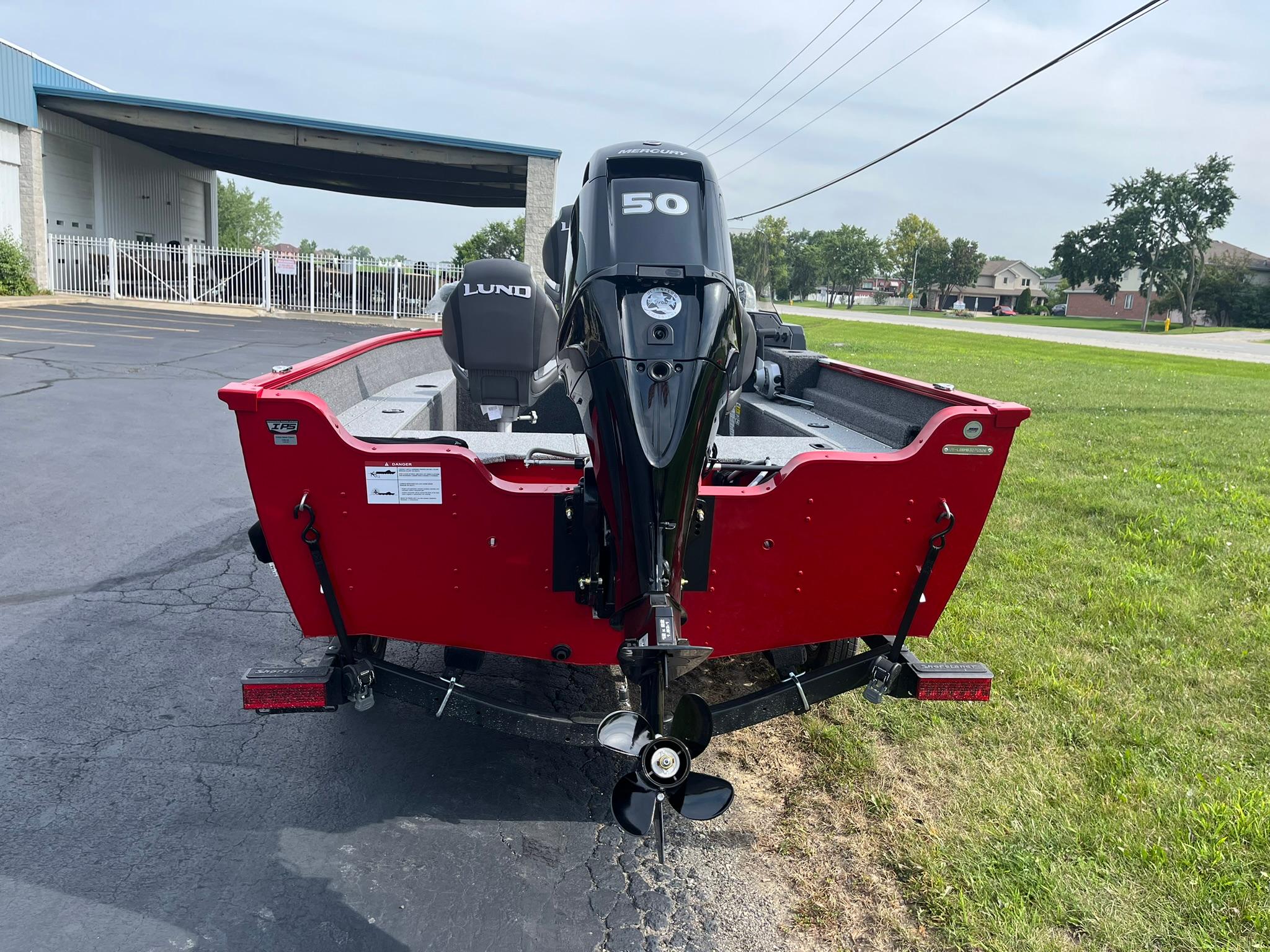 2026 Lund 1650 Angler SS boat with a 50 HP motor, parked on pavement.