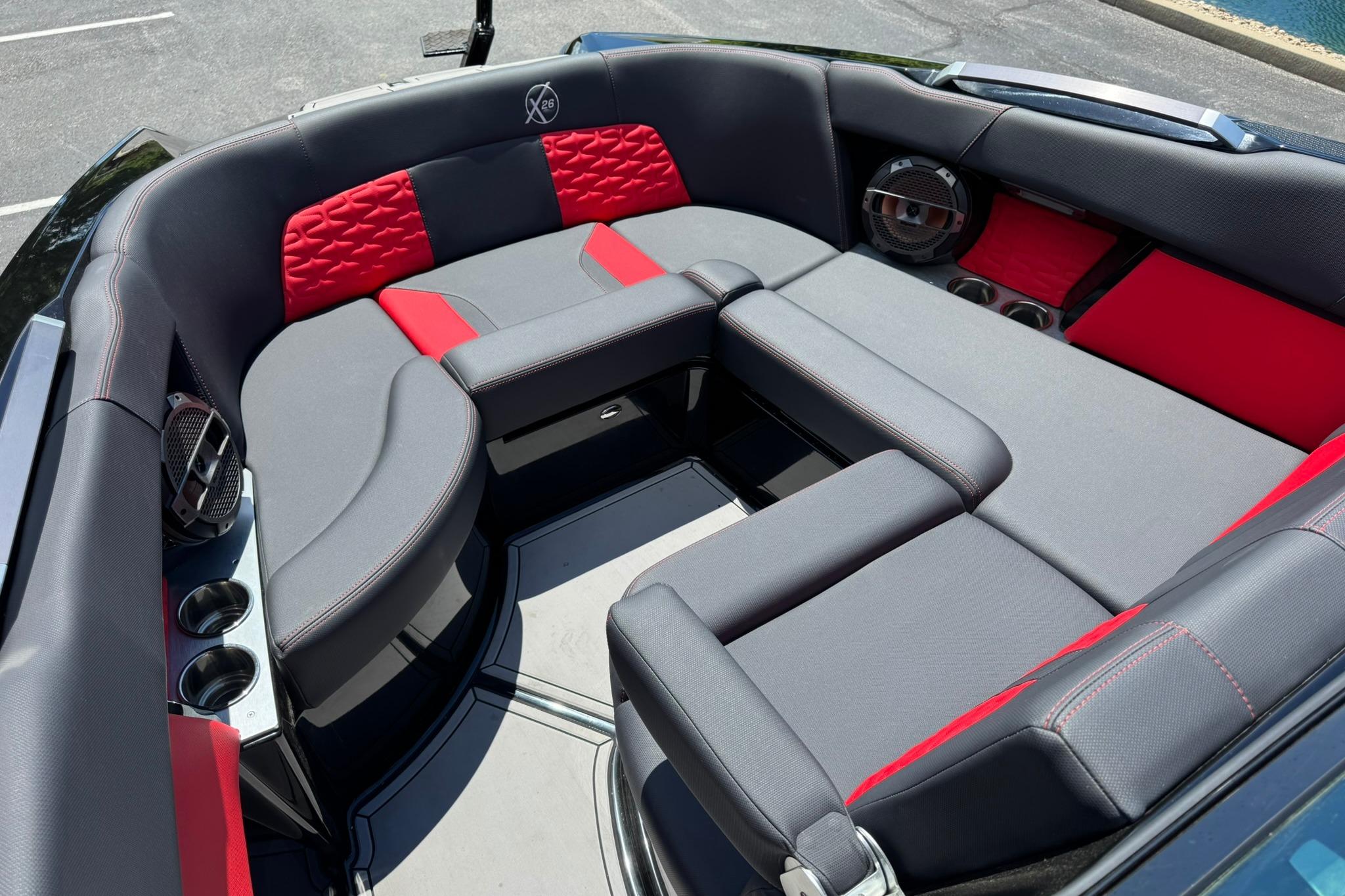 2021 MasterCraft X26 boat interior with gray and red seating, cup holders, and speakers.