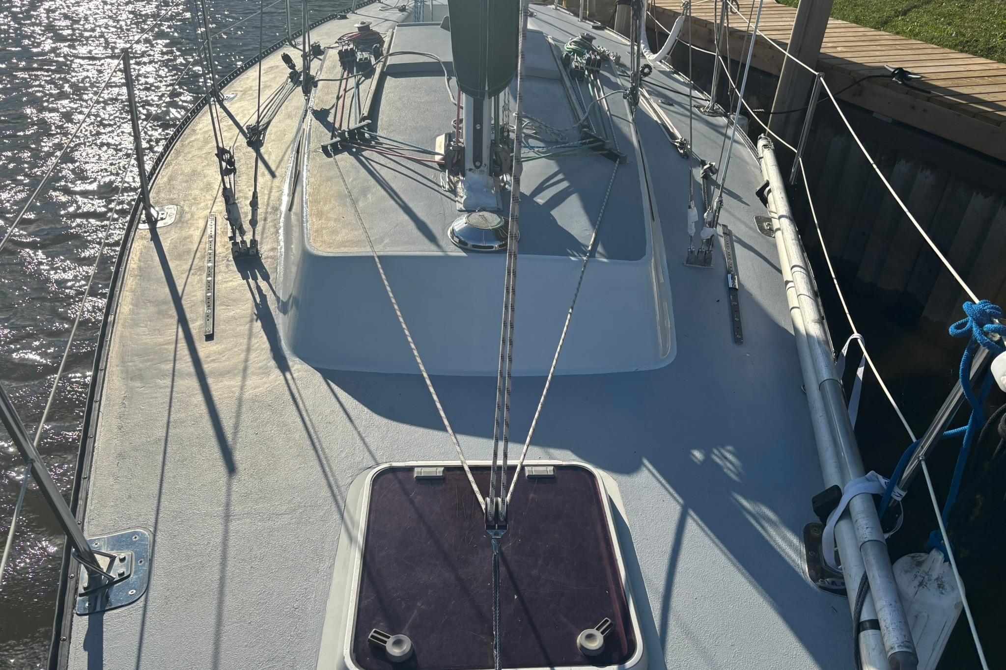 Sailboat deck of 1983 Evelyn 32, docked by the water.