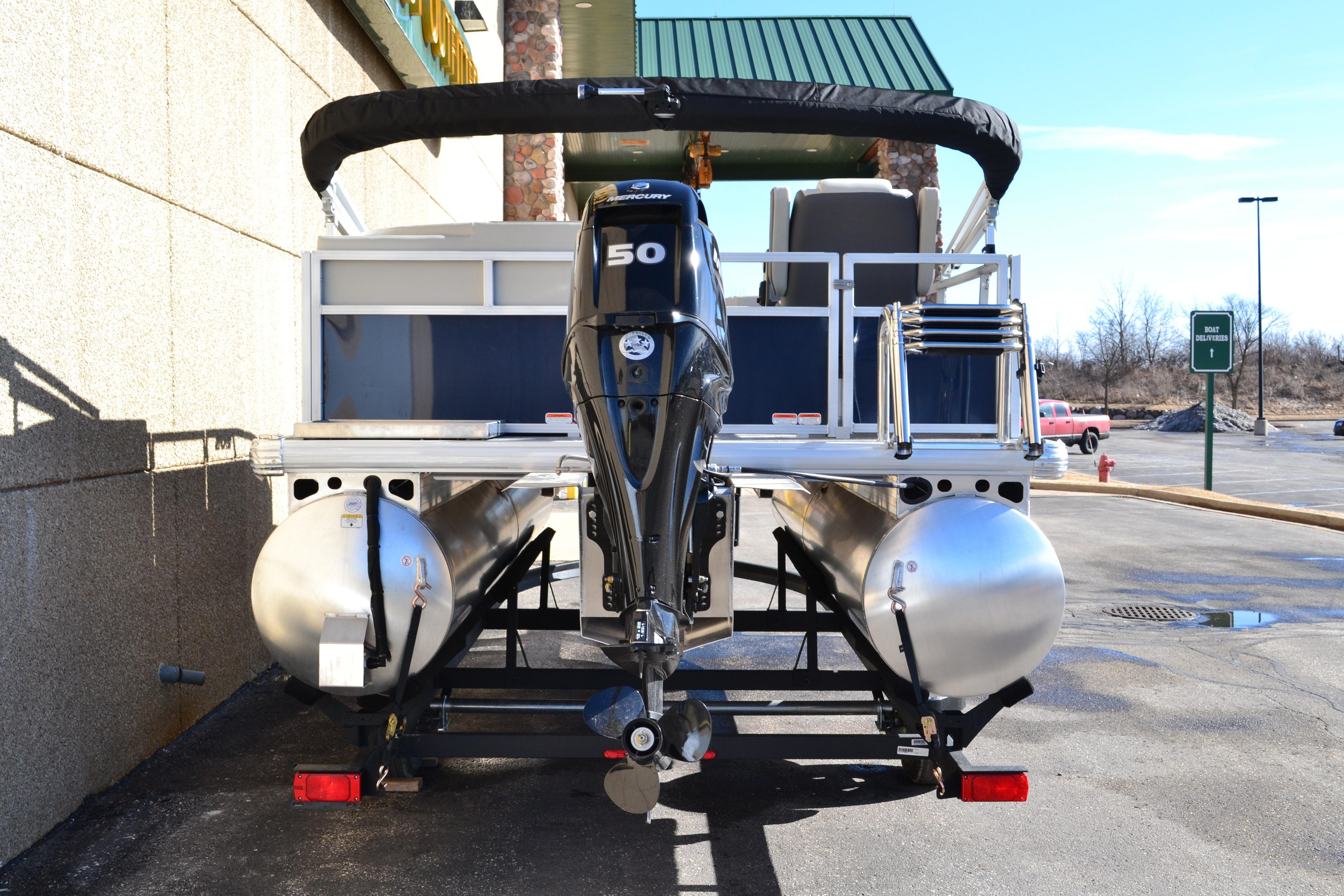 2026 Sun Tracker Bass Buggy 16 XL Select pontoon boat with 50 HP engine, parked outdoors.