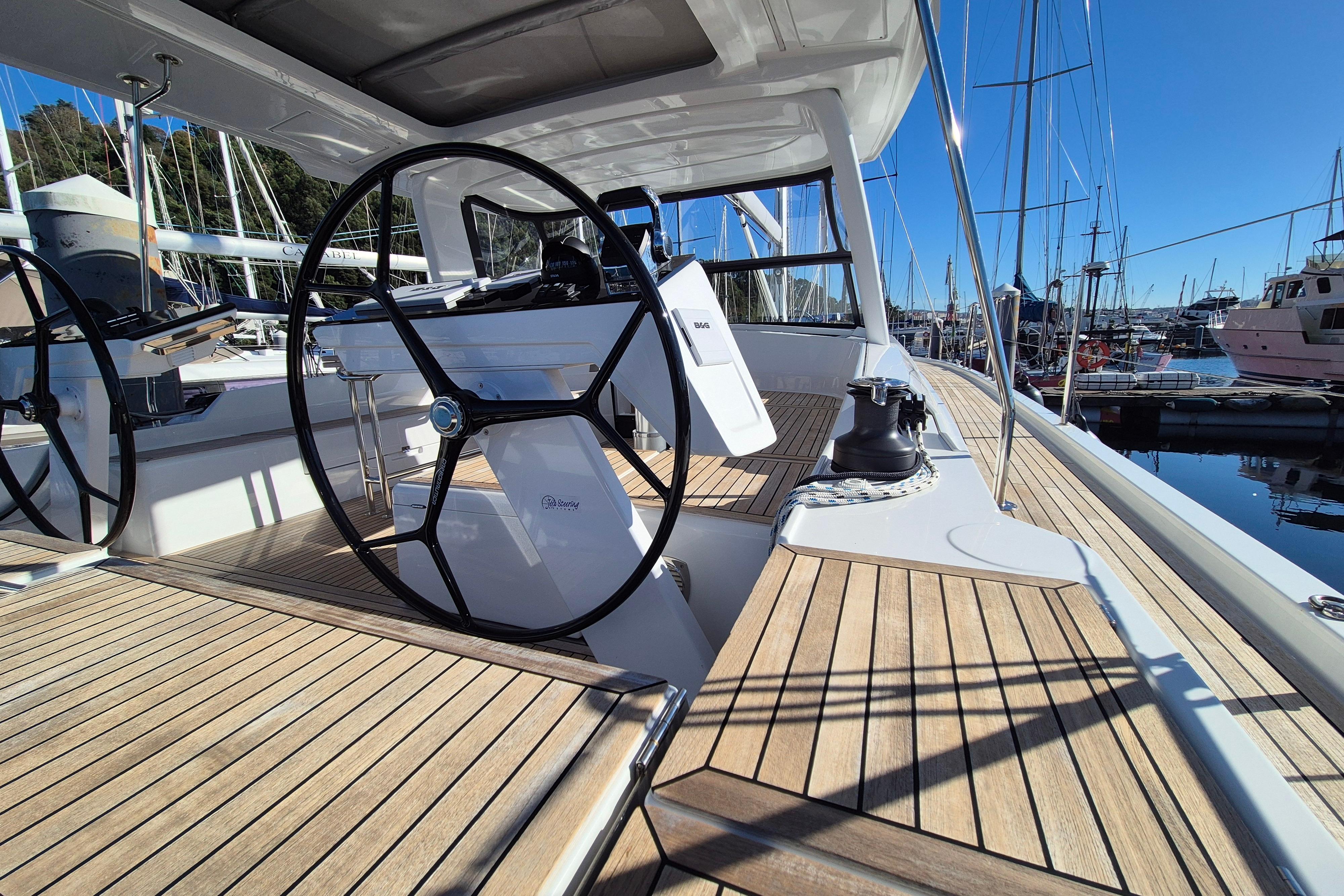 2024 Hanse 460 yacht deck with dual steering wheels and wooden flooring at marina.