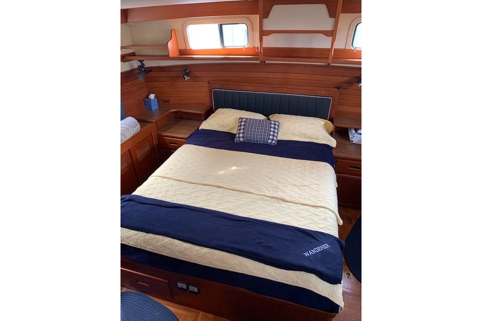Cozy bedroom interior of 1983 Grand Banks 42 Motoryacht with wooden paneling and nautical decor.