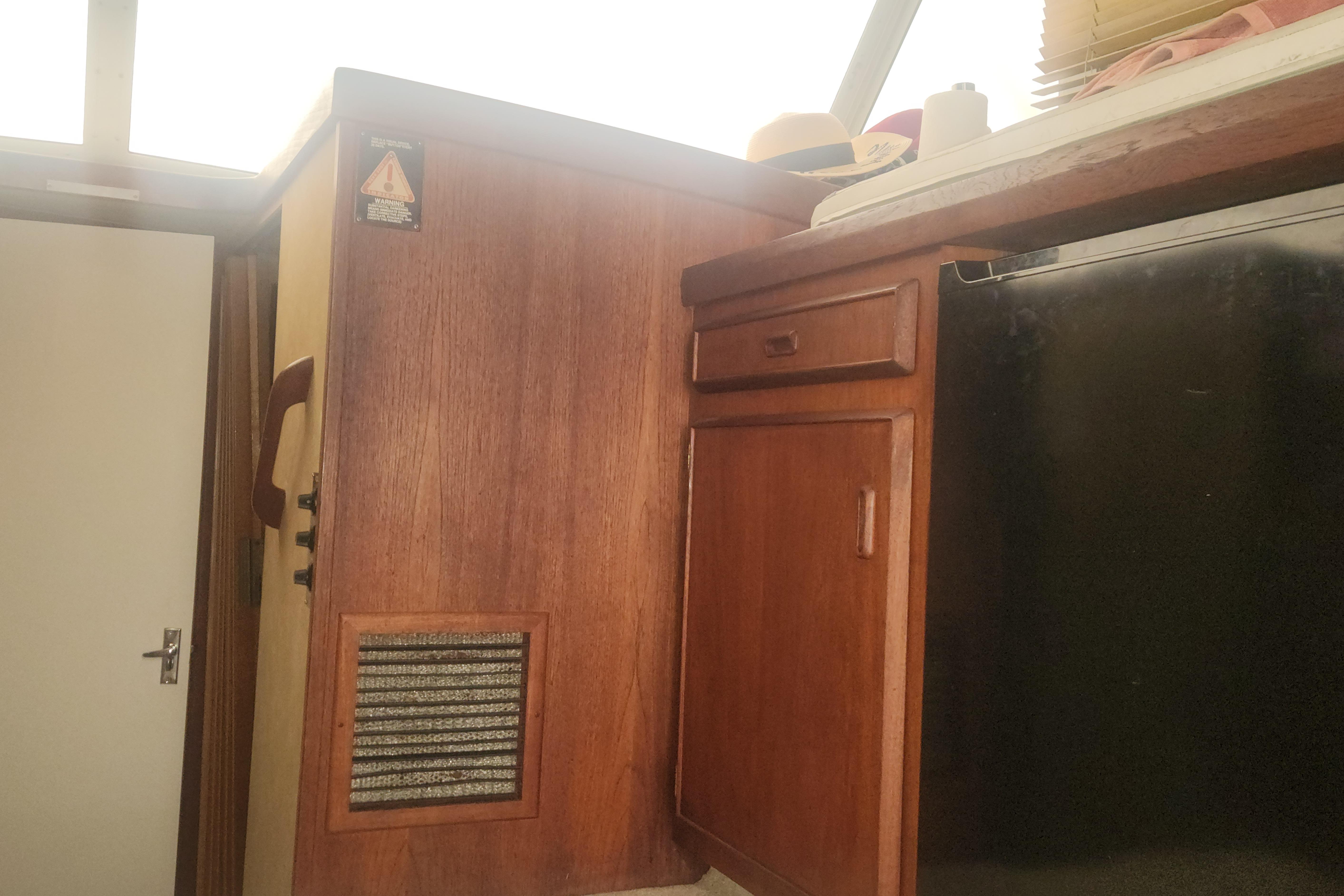 Interior of 1985 Bertram 33 Flybridge Cruiser with wooden cabinetry and door.