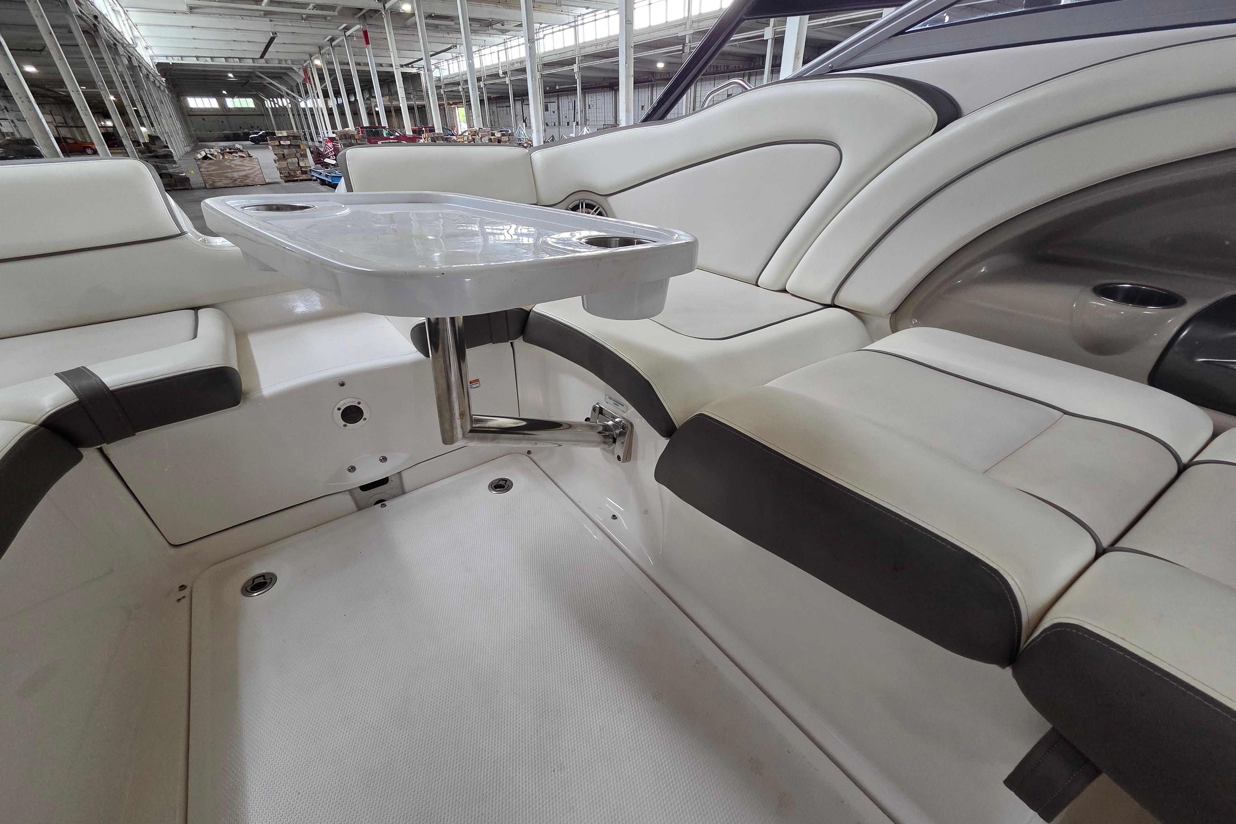 Interior of 2013 Yamaha 242 Limited S boat with seating and table in a warehouse.
