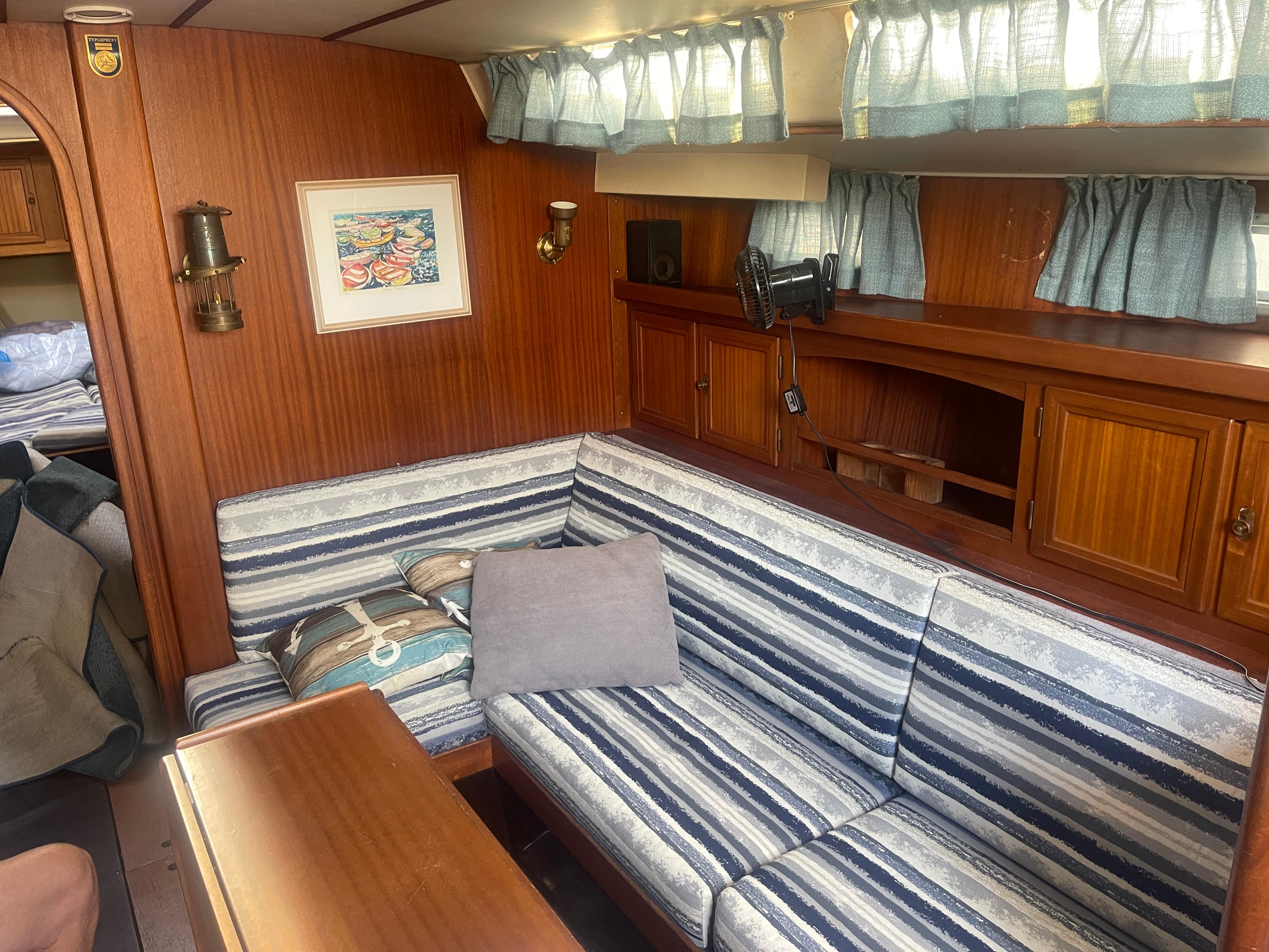 Cozy interior of 1984 Hanseat 37 sailboat with striped seating and wooden cabinetry.