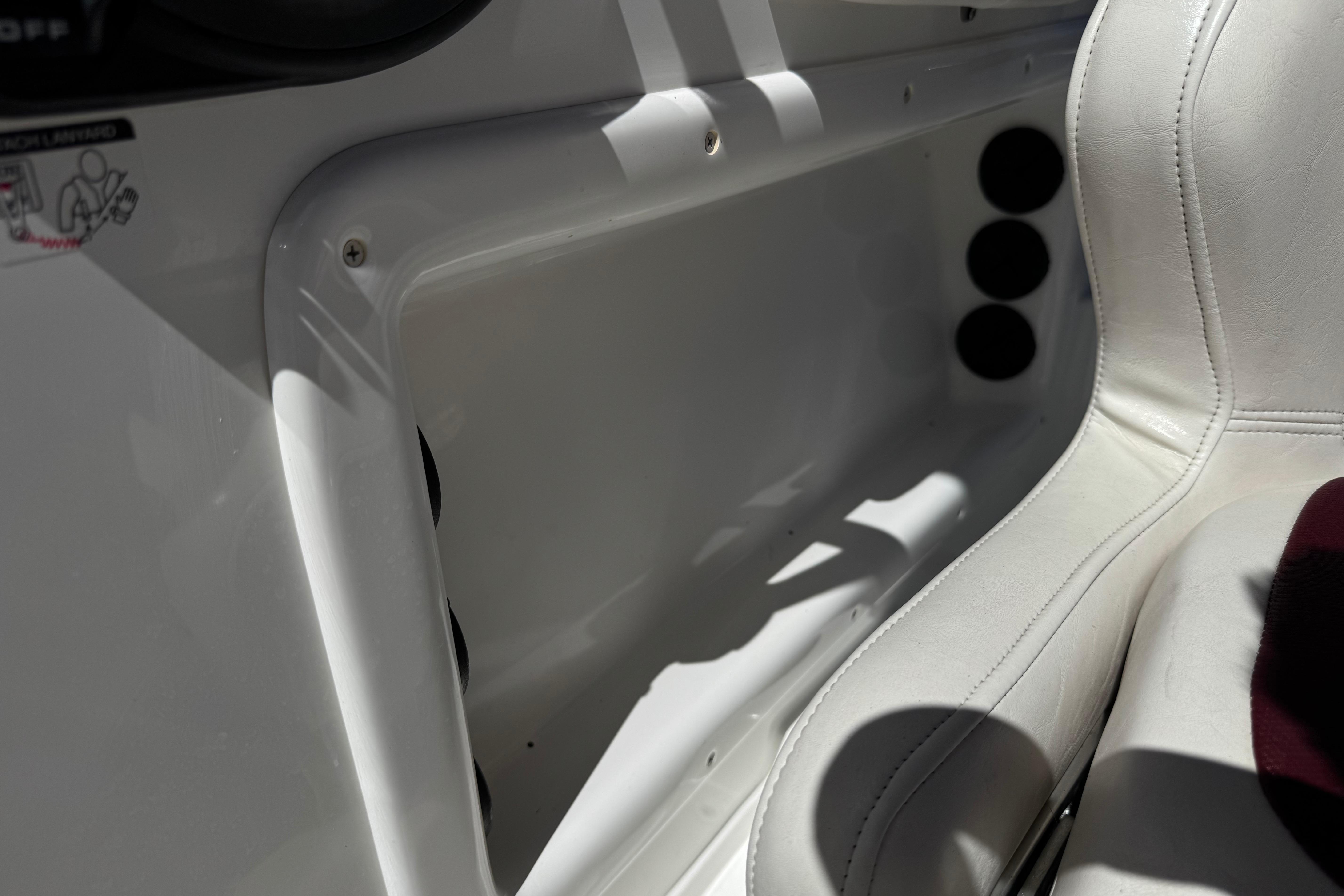 Interior of a 2017 Tahoe 2150 boat, featuring white seating and storage compartment.