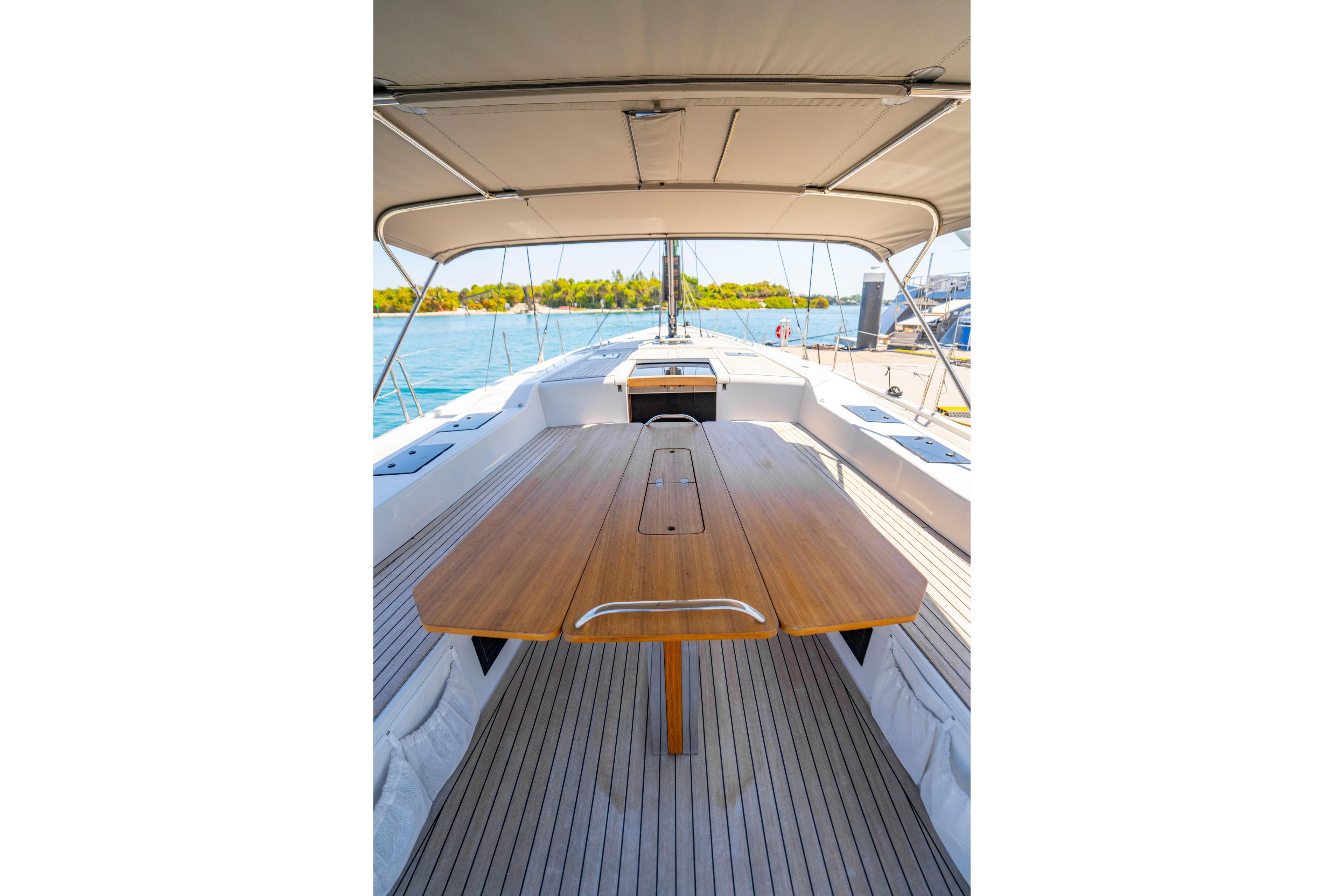 Spacious deck of 2016 Grand Soleil 58 yacht with wooden table and canopy.
