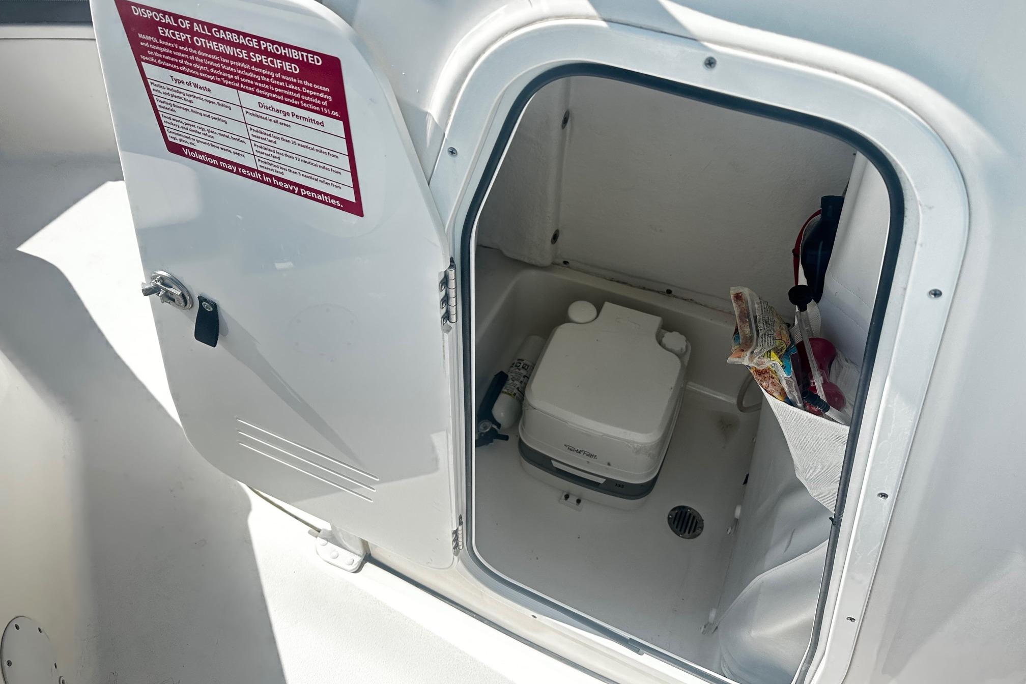 2020 Tidewater 230 CC Adventure boat storage compartment with portable toilet and storage pocket.