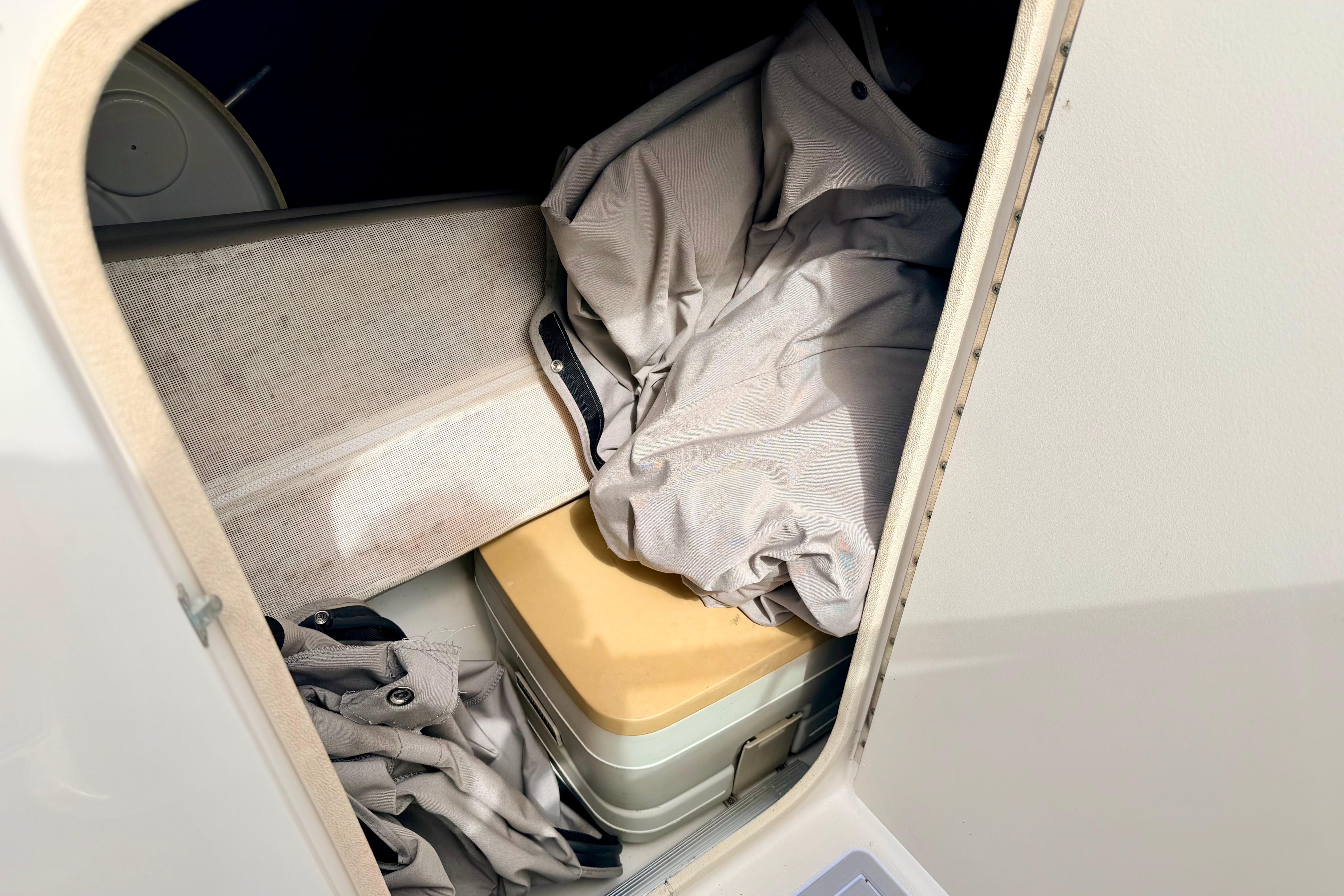 Storage compartment in a 2003 Sea Ray 200 Sundeck boat, containing folded fabric and a box.