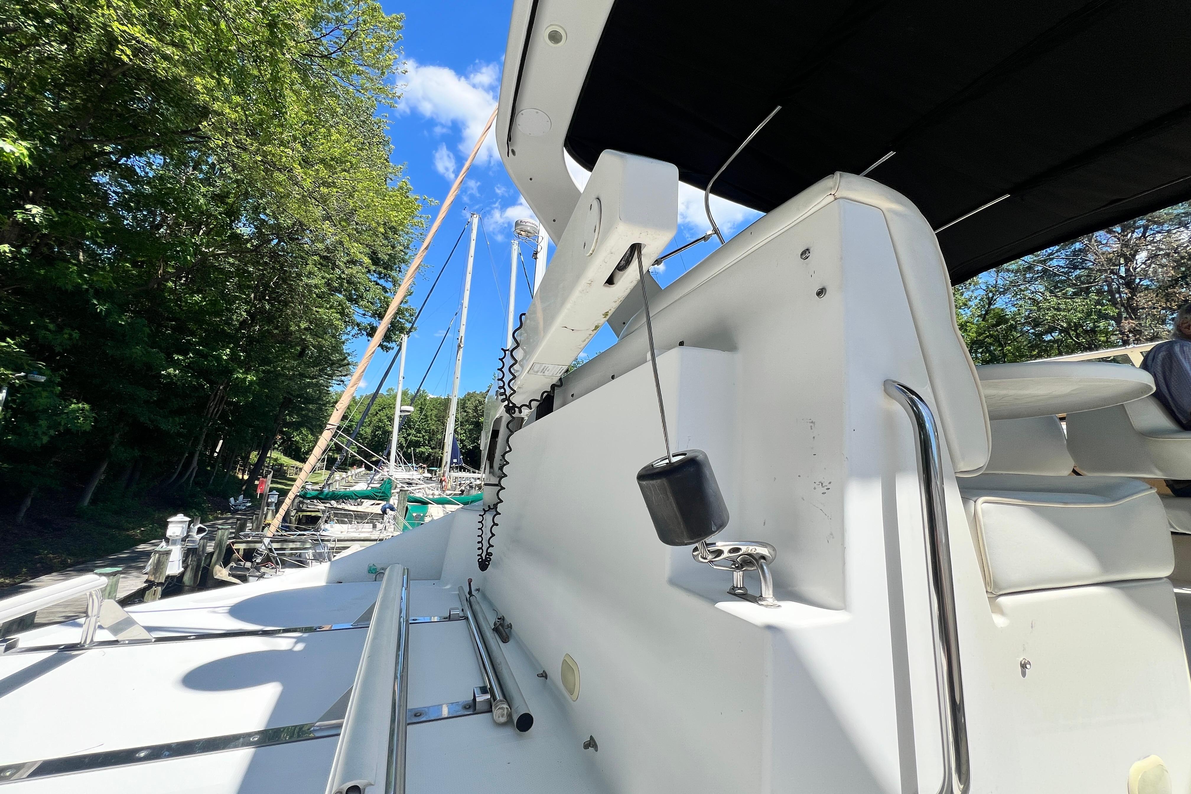 2003 Carver 450 Voyager Pilothouse yacht docked, featuring sleek white design and lush green surroundings.