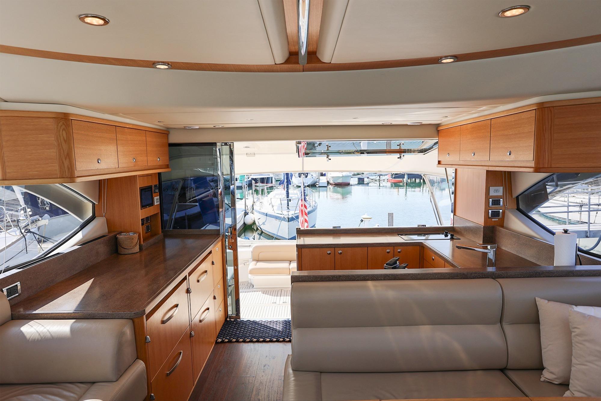 Interior of 2016 Riviera 525 SUV yacht with modern wood cabinetry and marina view.