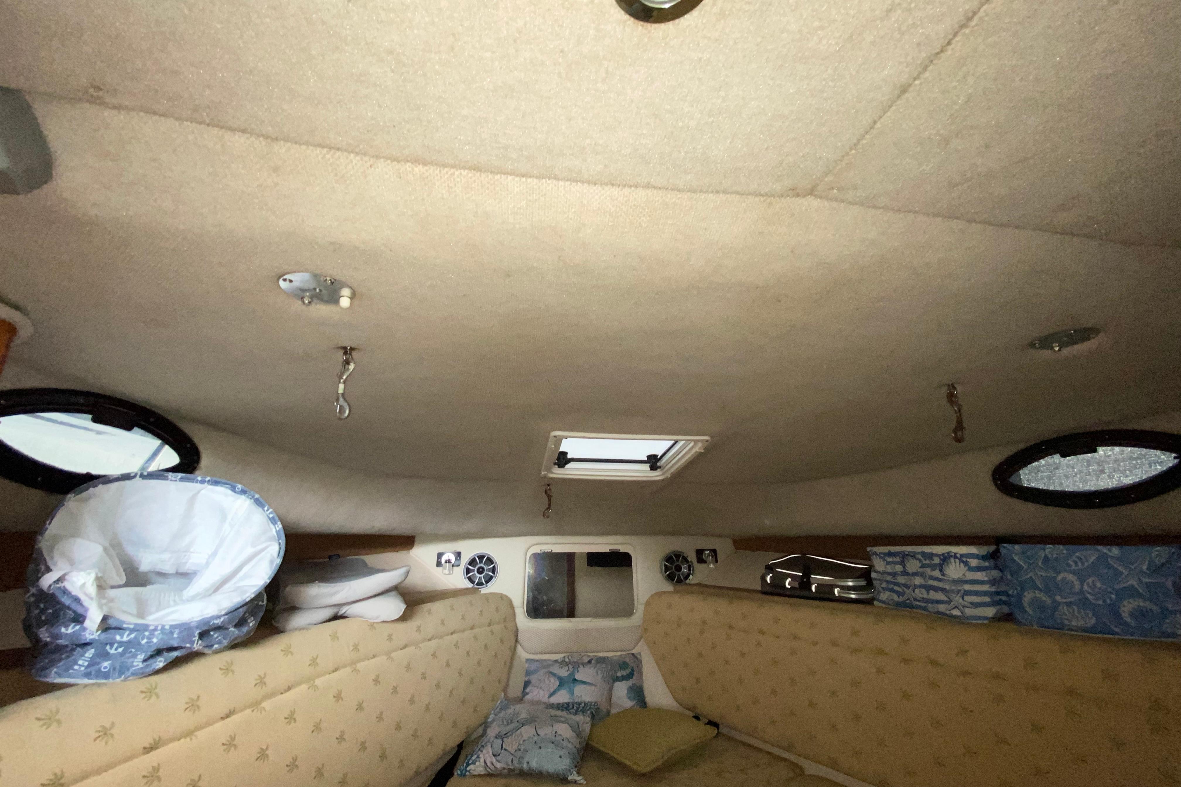 Interior cabin of 2005 Wellcraft 290 Coastal boat with beige upholstery and portholes.