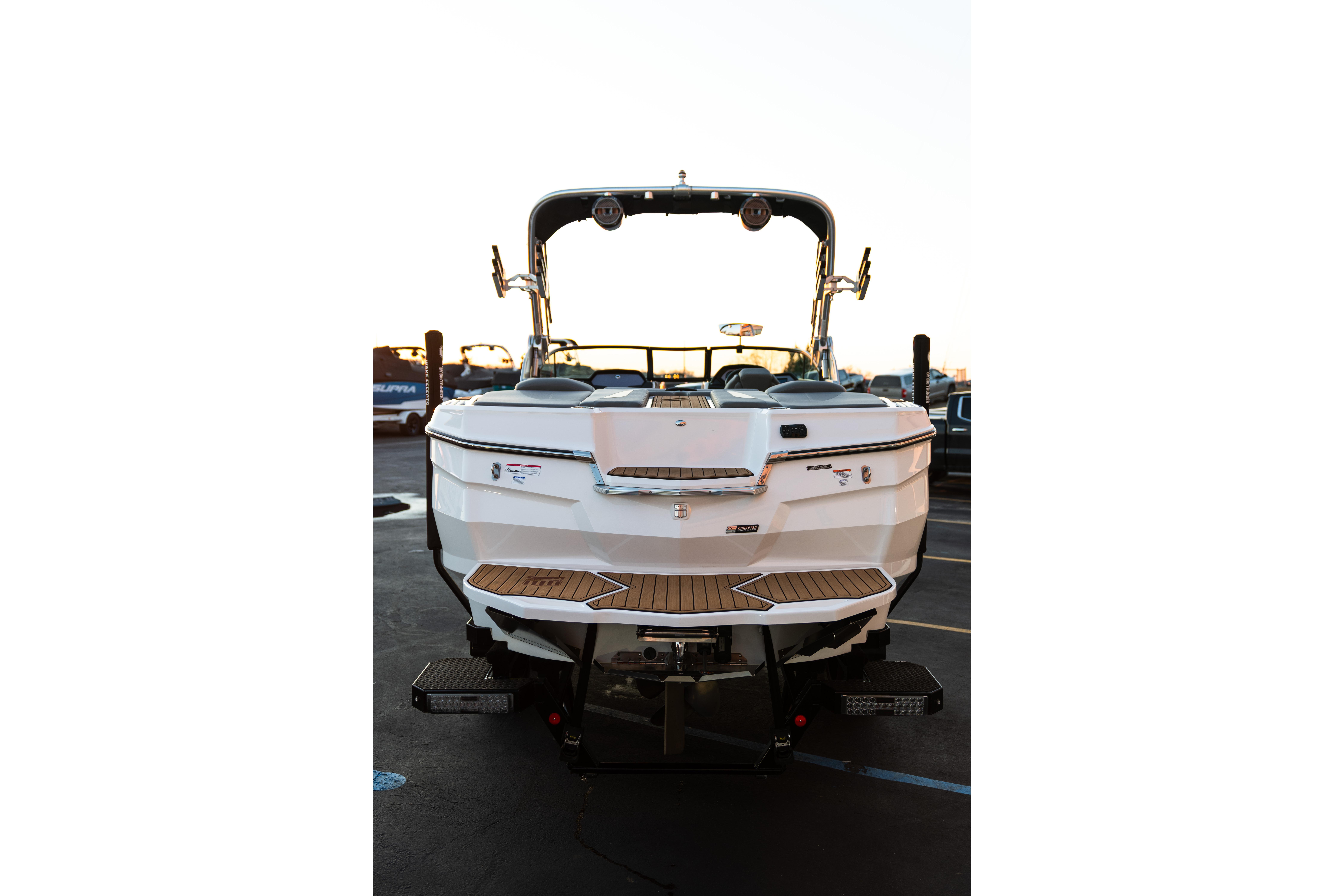 2022 MasterCraft XStar boat rear view with teak swim platform in a parking lot.