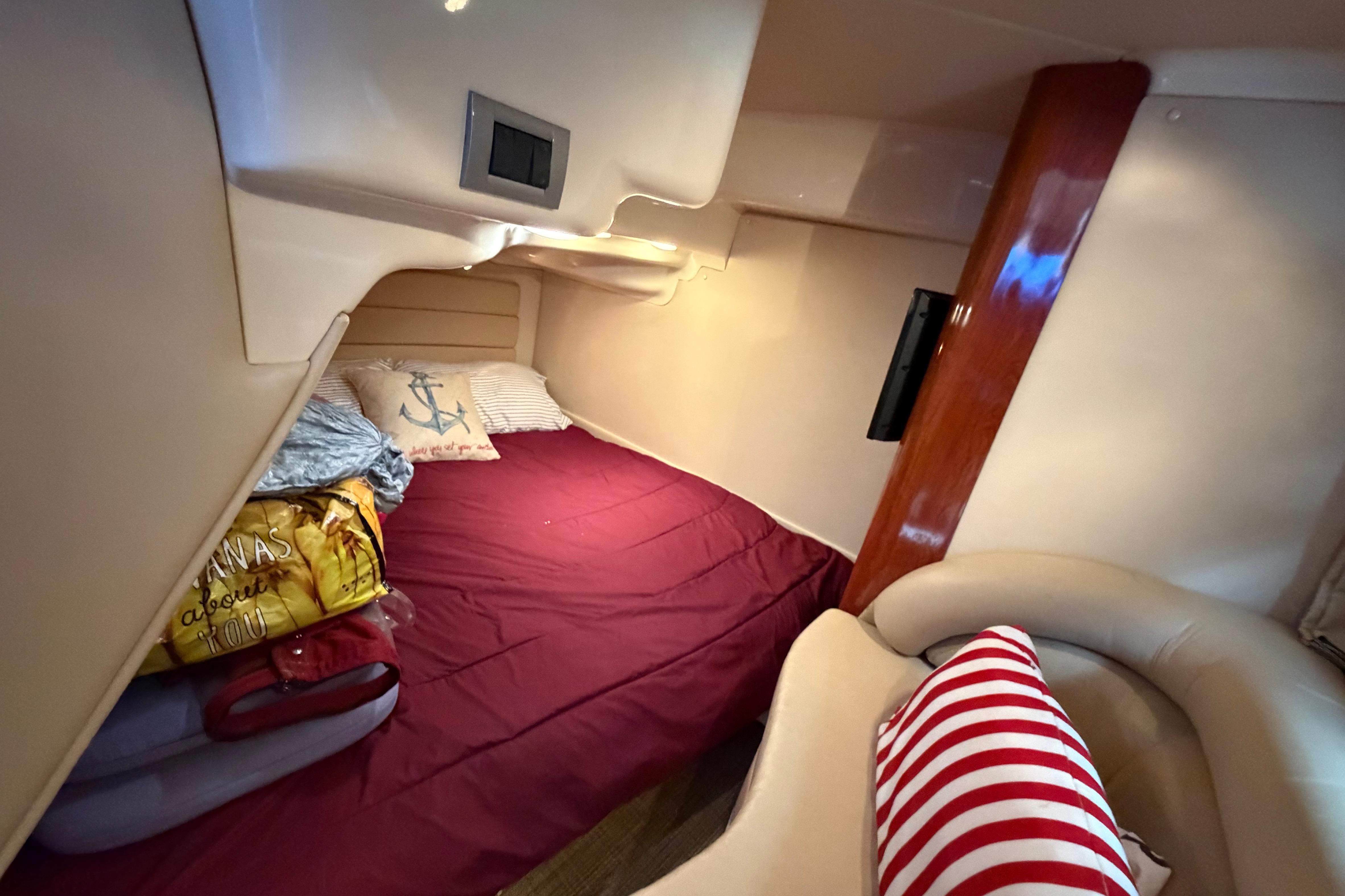 Cozy cabin interior of 2007 Monterey 350 Sport Yacht with red bedding and nautical decor.