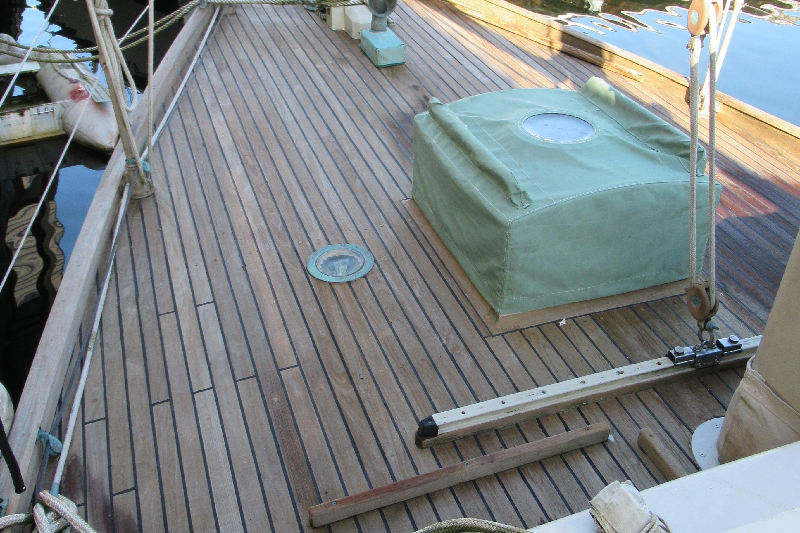 Wooden deck of a 1979 Worldcruiser schooner with green cover and nautical equipment.