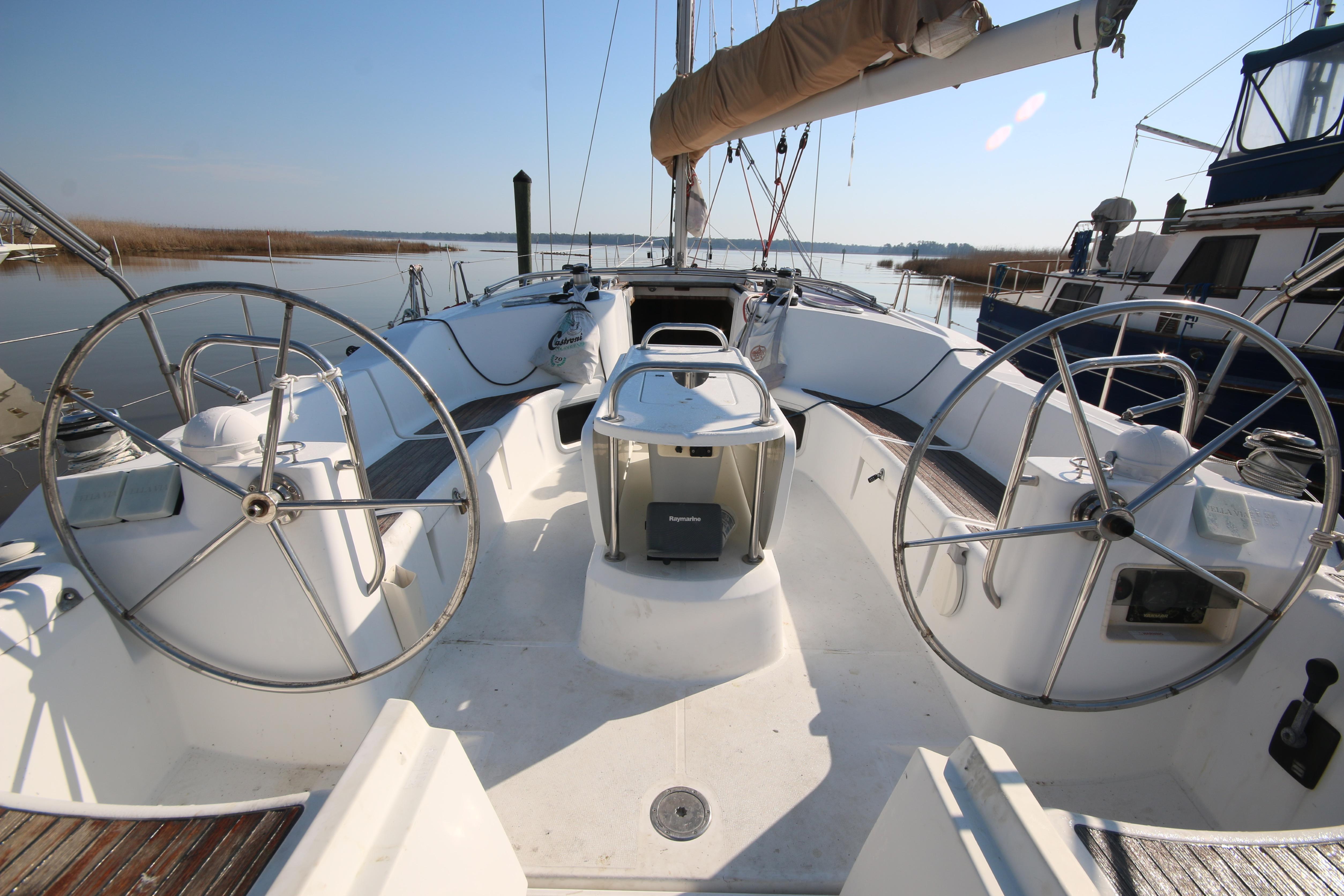 2009 Jeanneau Sun Odyssey 44i sailboat cockpit with dual steering wheels, docked in a marina.