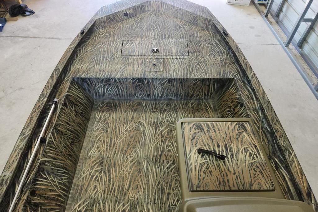 2026 Tracker Grizzly 1648 SC boat with camouflage pattern in a garage setting.