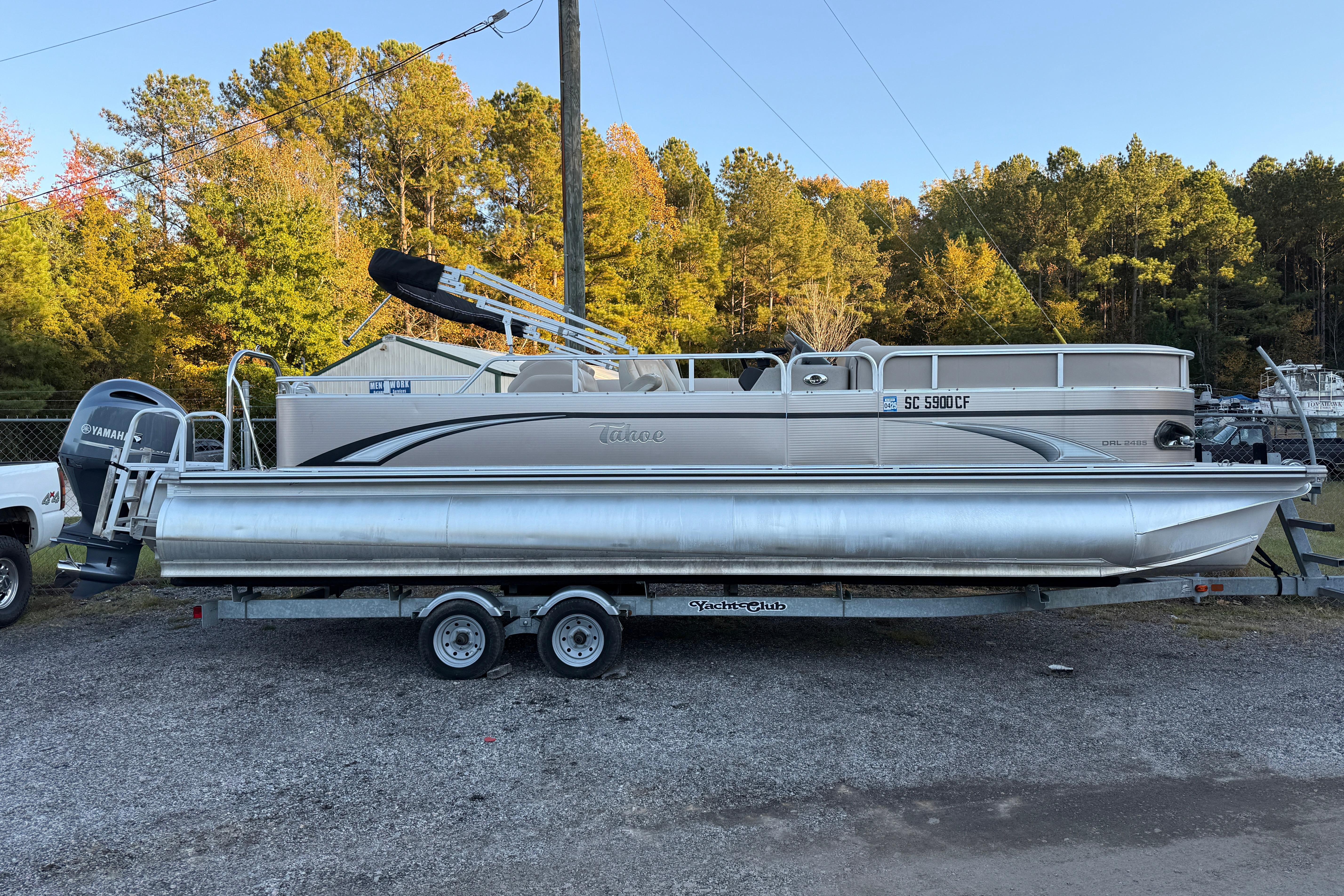 2011 Tahoe Pontoon 2485 DRL on trailer, parked outdoors with trees in background.