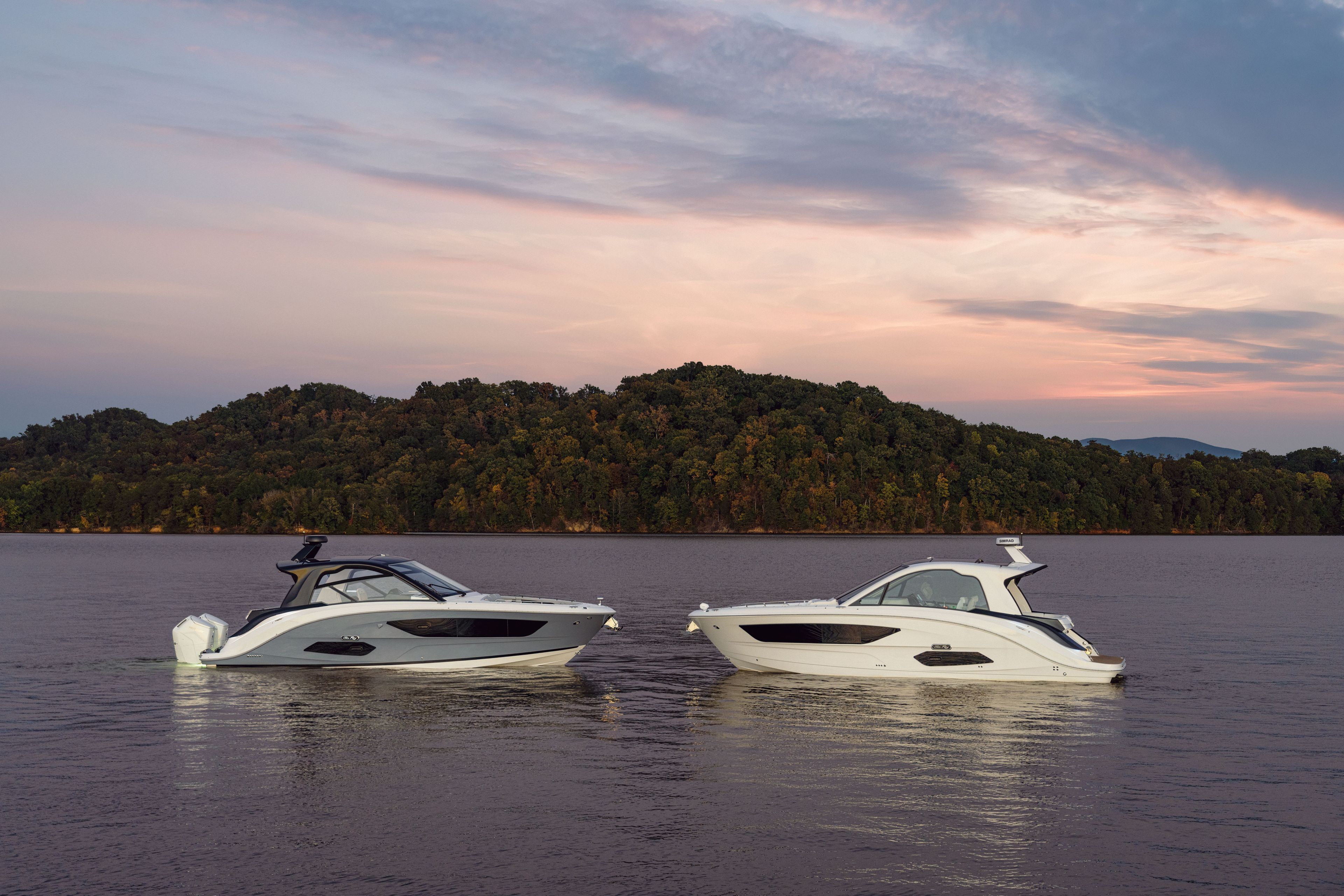 Two Sea Ray Sundancer 370 Outboard boats float on calm water at sunset.