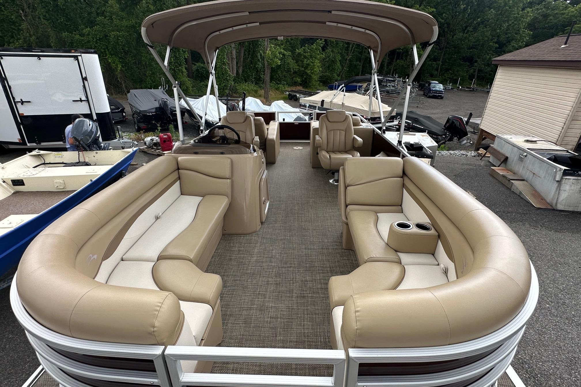 2016 Bennington 24 SCWX pontoon boat with beige seating and canopy, parked outdoors.